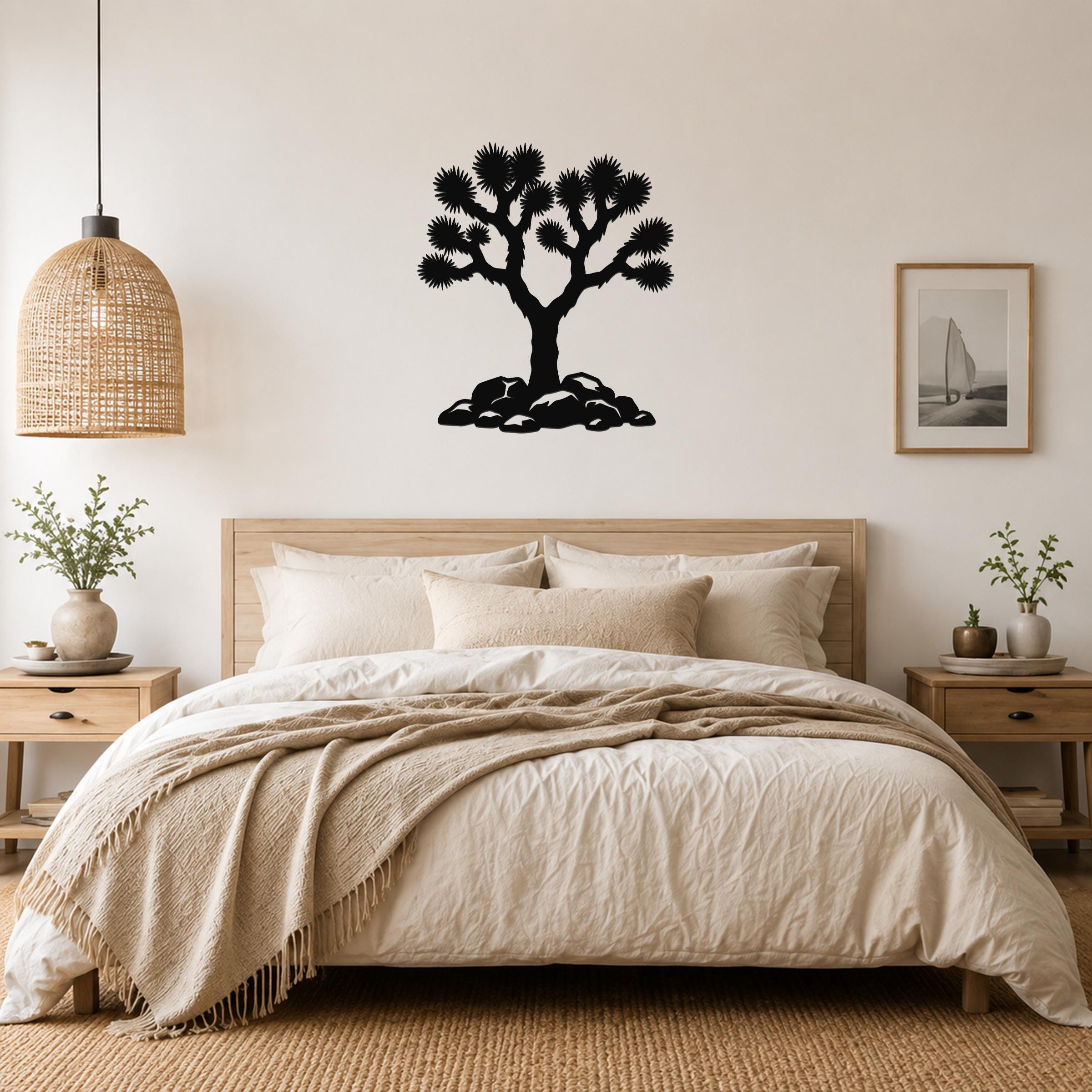 Black metal Joshua tree wall art with detailed branch cutouts, mounted above a bed in a neutral bedroom.