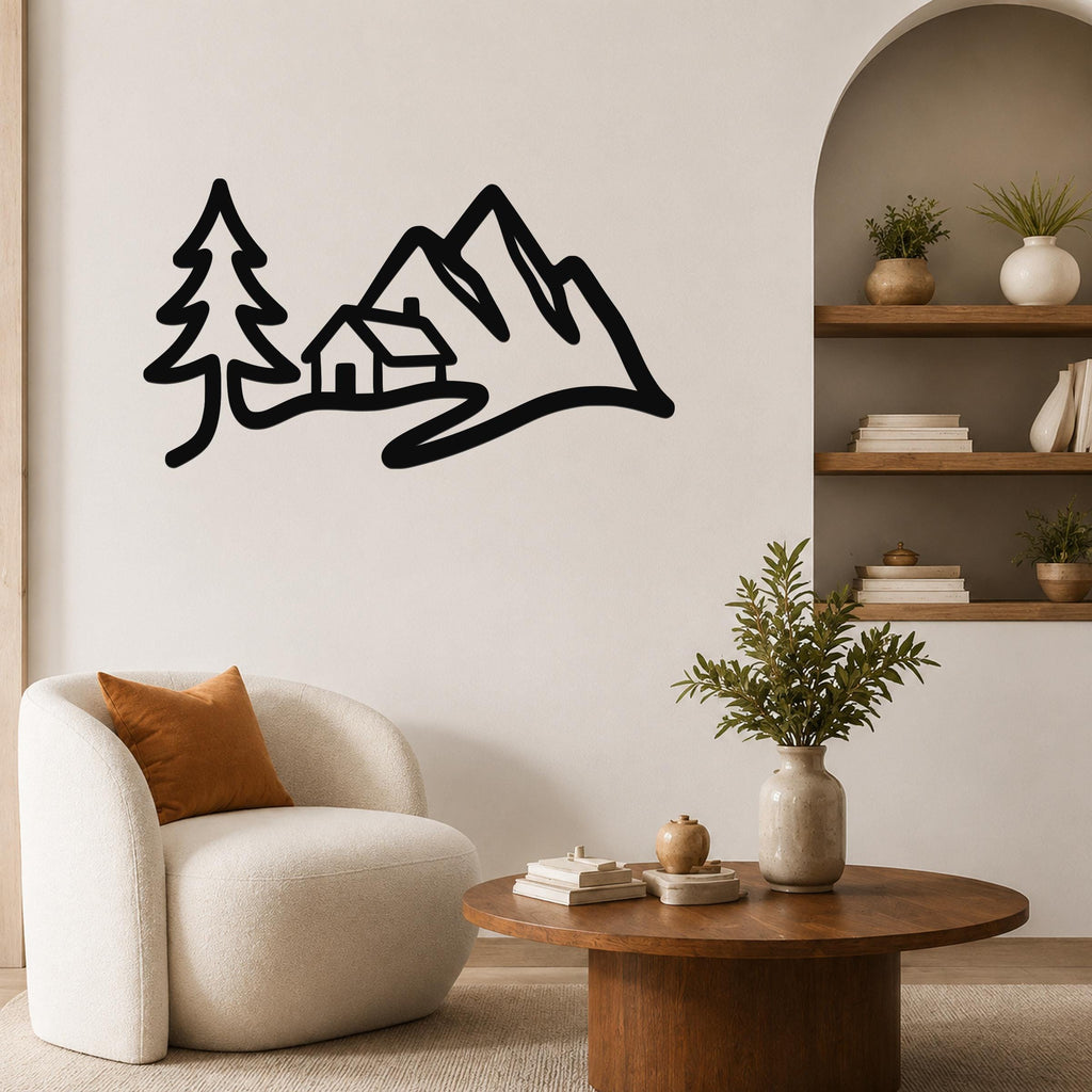 Black metal wall art silhouette of a mountain cabin with trees, mounted on a living room wall above a white armchair.