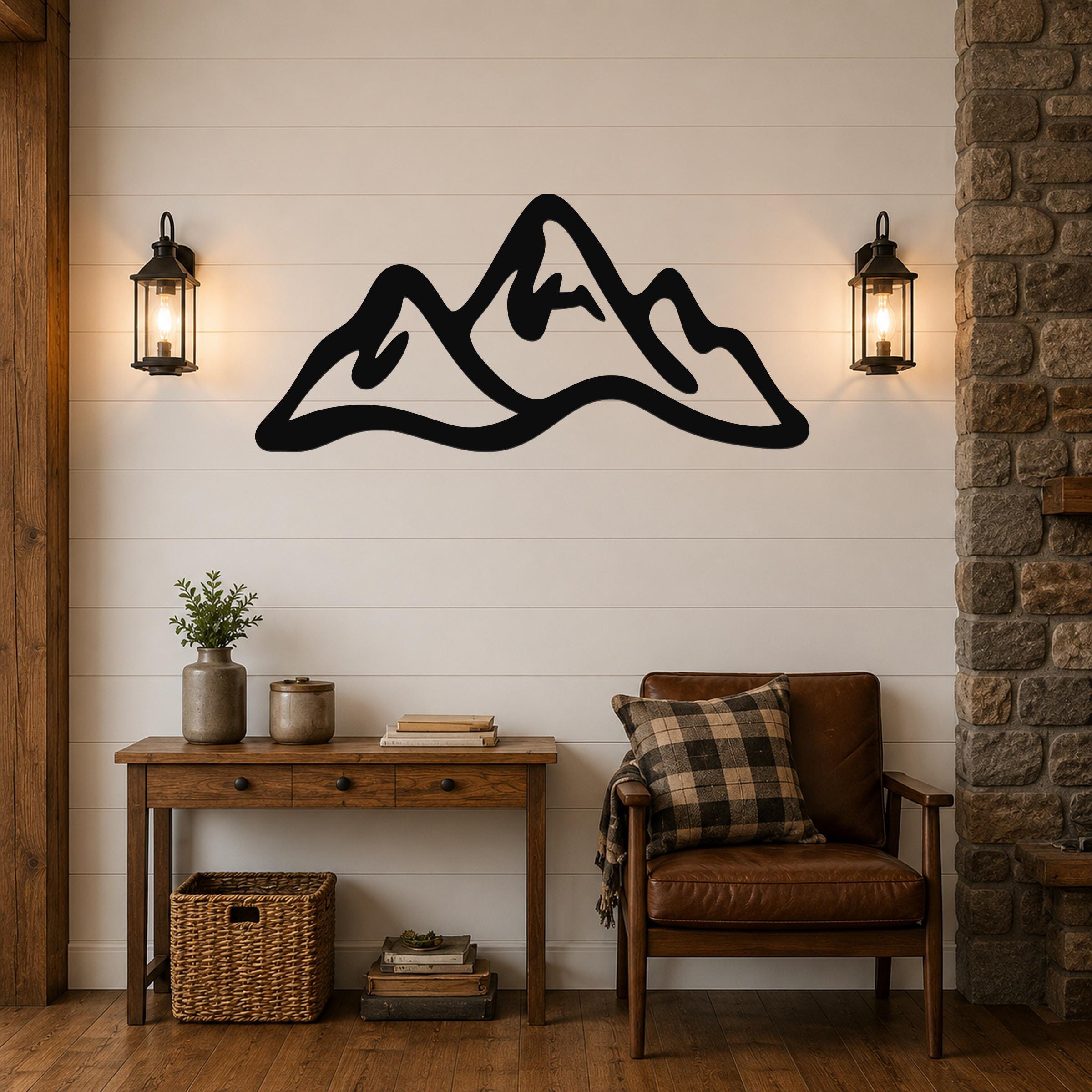 Black metal mountain range wall art with a bold silhouette design, mounted on a shiplap wall above a wooden console table in a rustic living room.
