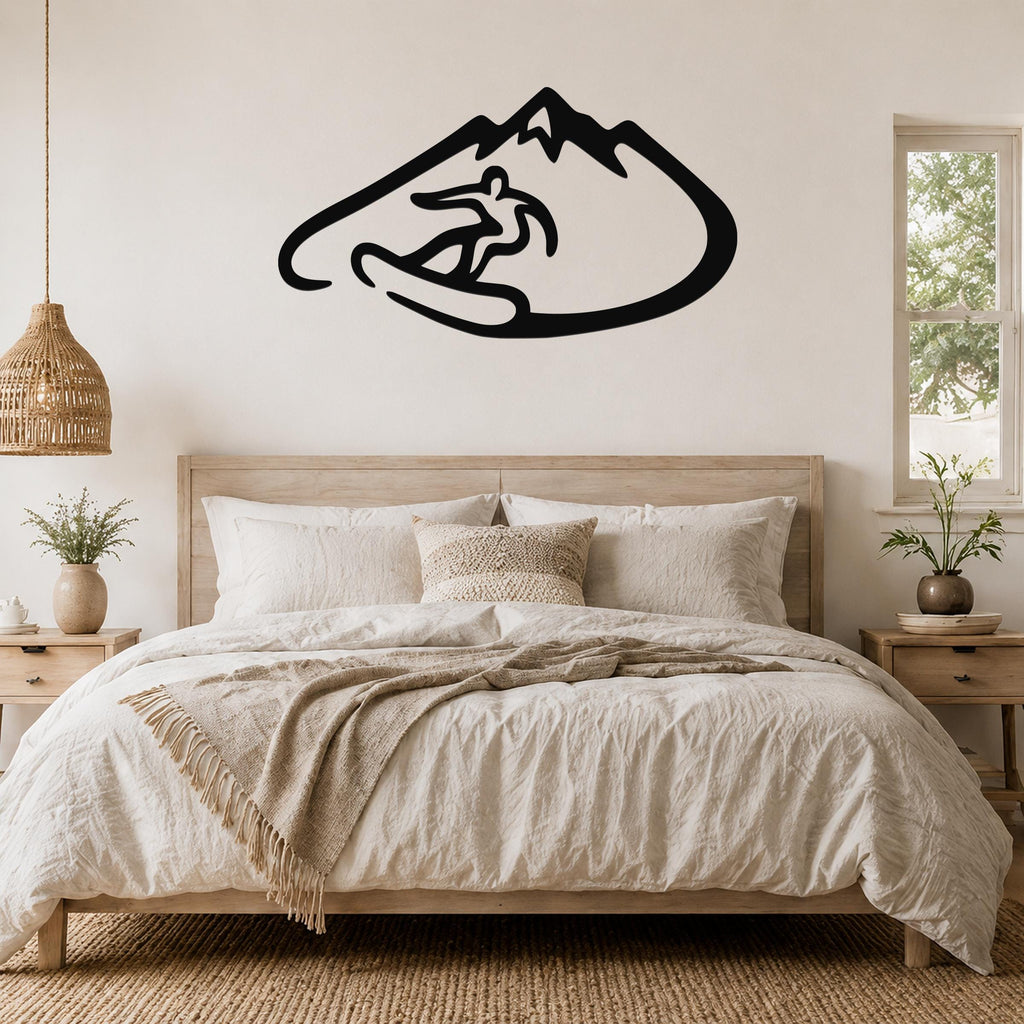 Black metal wall art featuring a snowboarder silhouette inside a mountain outline, mounted above a bed in a bedroom.