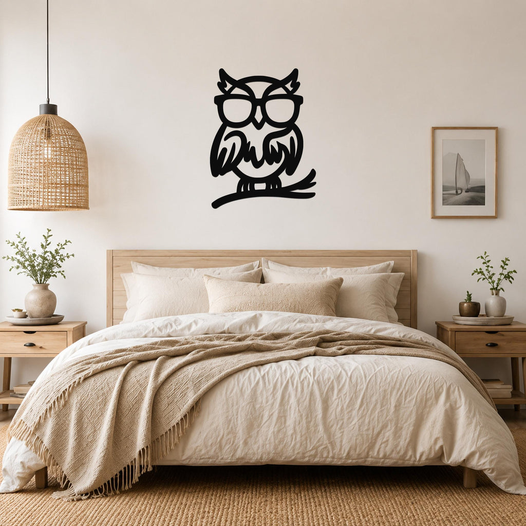 Black metal owl wall art with glasses and a branch silhouette, mounted above a bed in a neutral bedroom.
