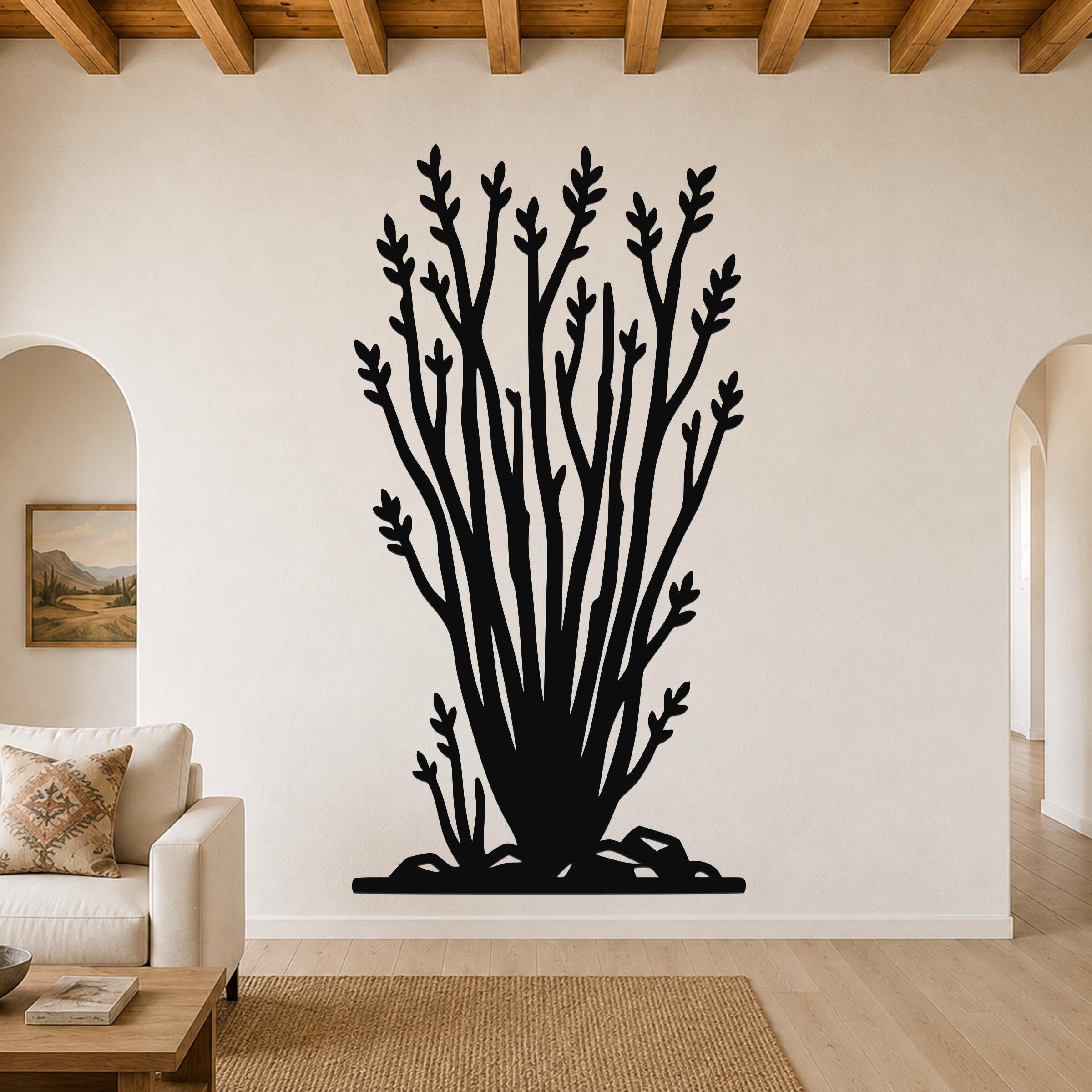 Black metal ocotillo wall art with branching cutouts, mounted on a living room wall above a sofa.