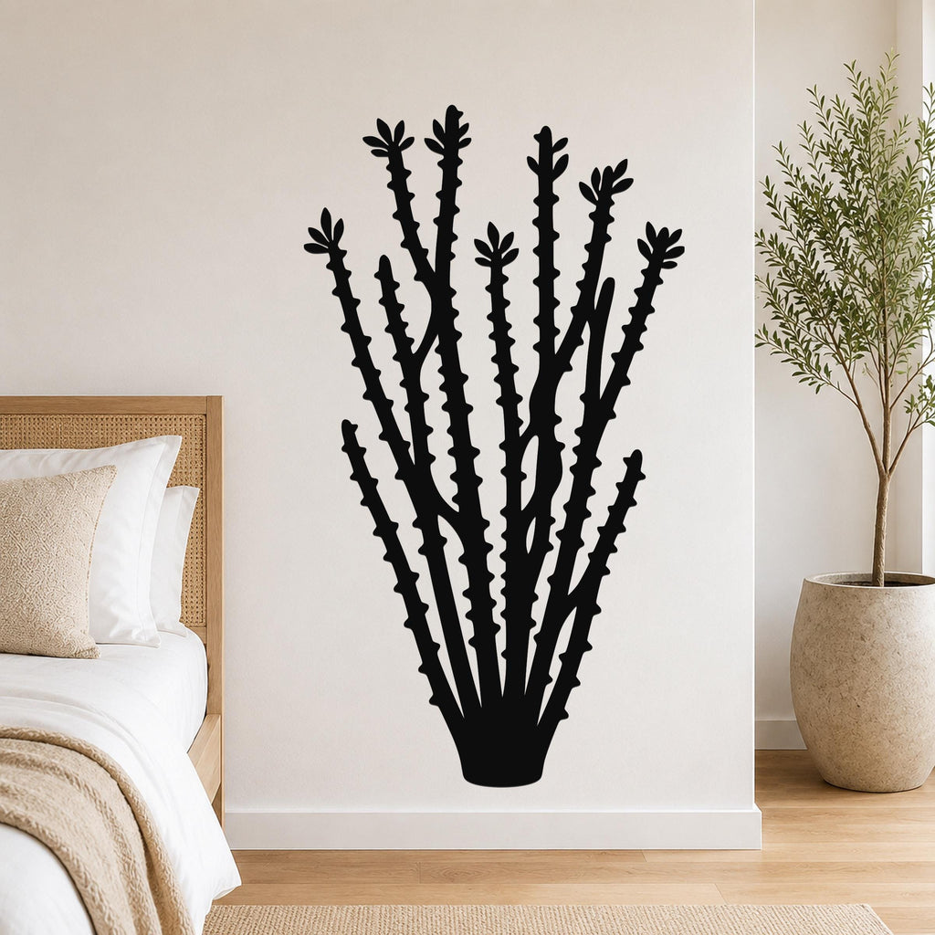 Black metal ocotillo wall art silhouette with spiny branches and leaf cutouts, mounted on a bedroom wall above a bed.