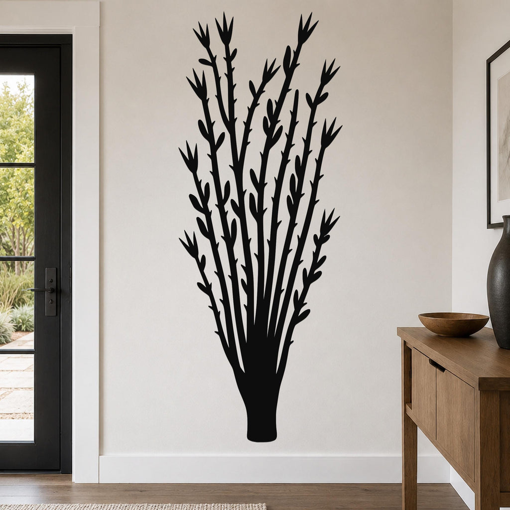Black metal wall art silhouette of an ocotillo plant with branching stems and leaf cutouts, mounted on a light-colored wall in a modern entryway.