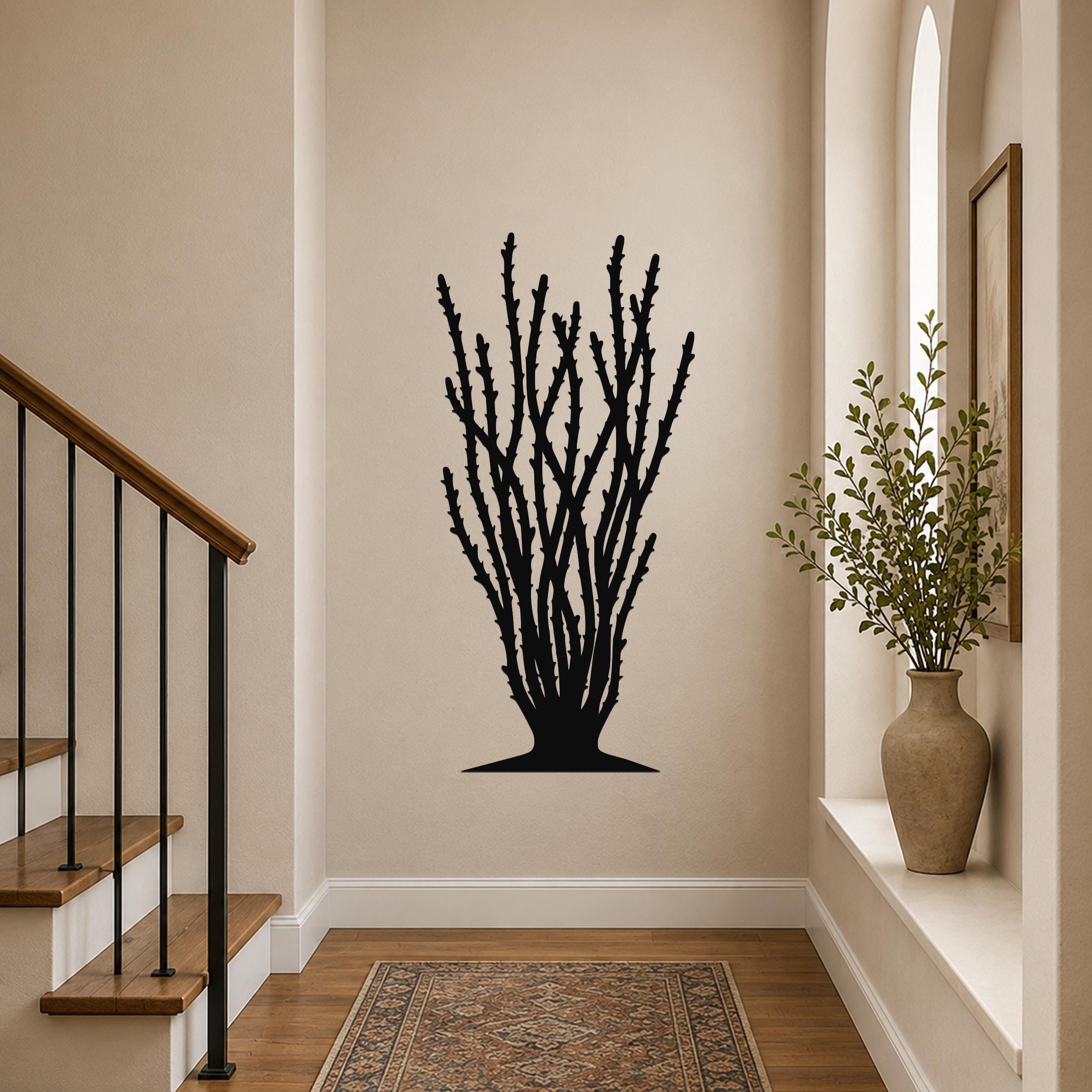 Black metal ocotillo wall art with spiny branch cutouts, mounted on a hallway wall above a patterned rug.