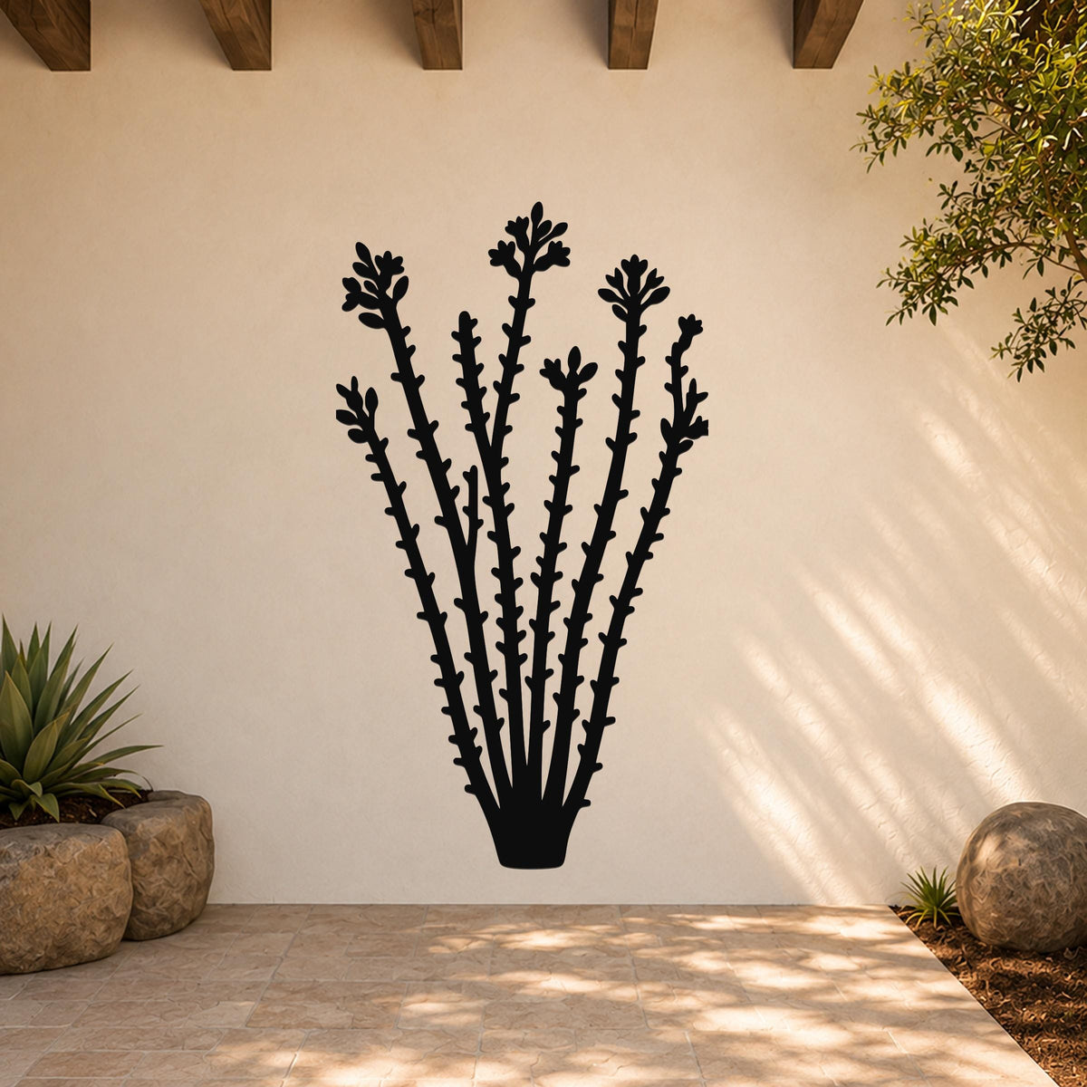 Black metal ocotillo wall art with flower and branch cutouts, mounted on a beige outdoor wall above a tiled patio.