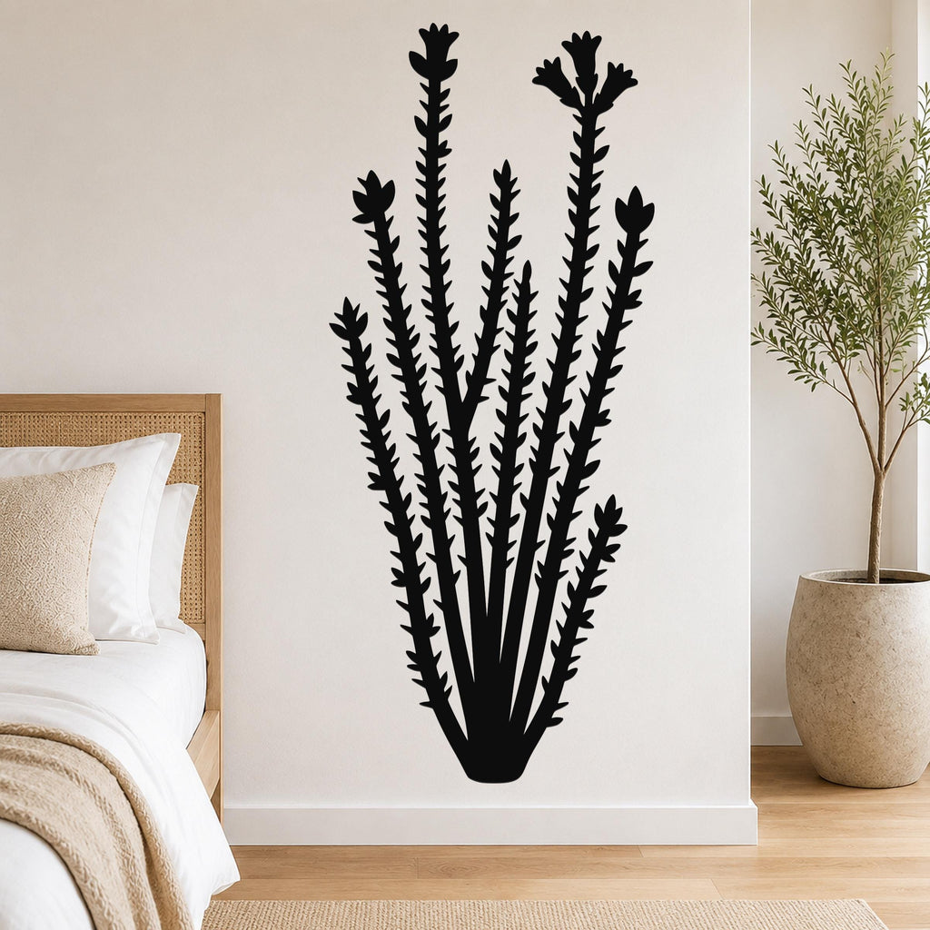 Black metal ocotillo wall art with spiny stems and flower cutouts, mounted on a white bedroom wall above a bed.