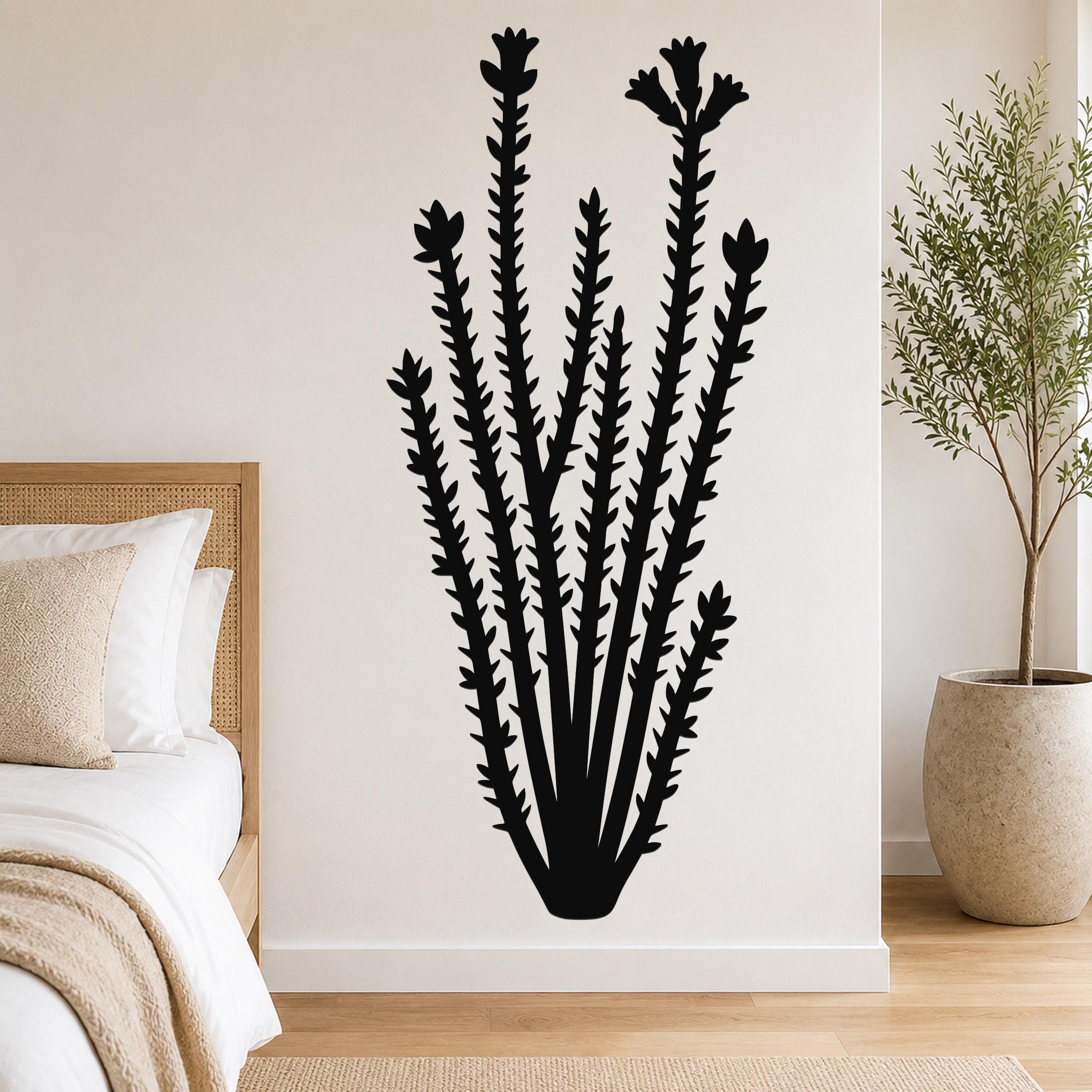 Black metal ocotillo wall art with spiny stems and flower cutouts, mounted on a white bedroom wall above a bed.