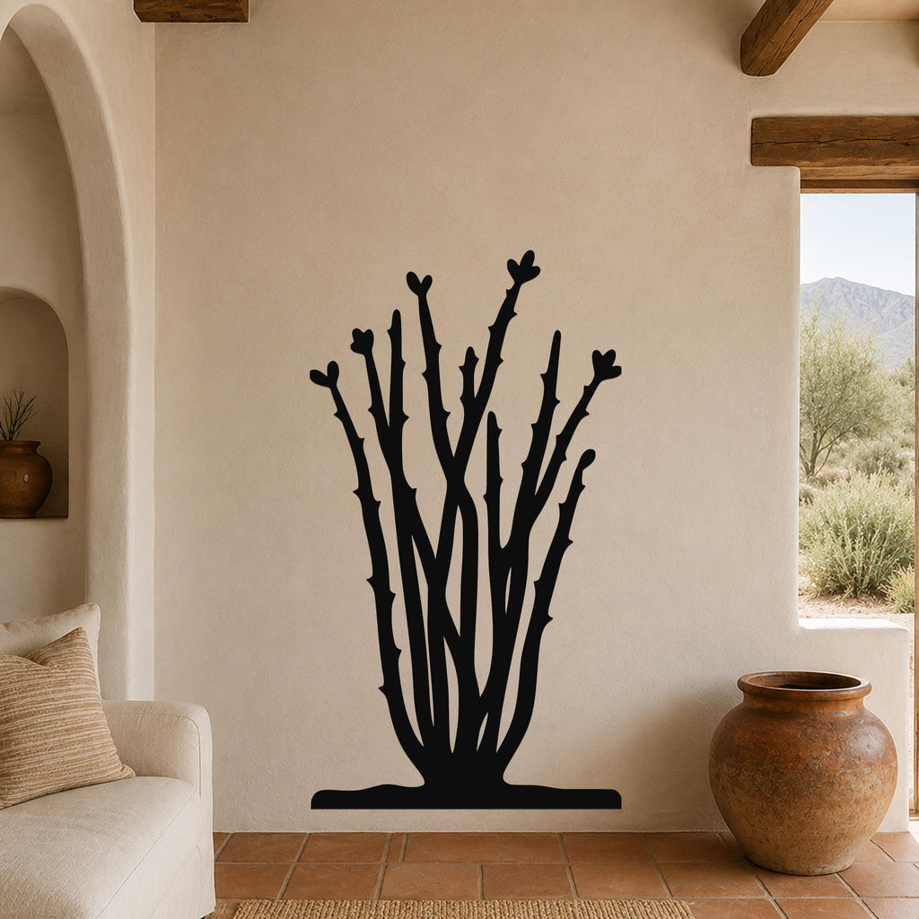 Black metal ocotillo wall art with branching stems and heart-shaped tips, mounted on a beige living room wall above a sofa.