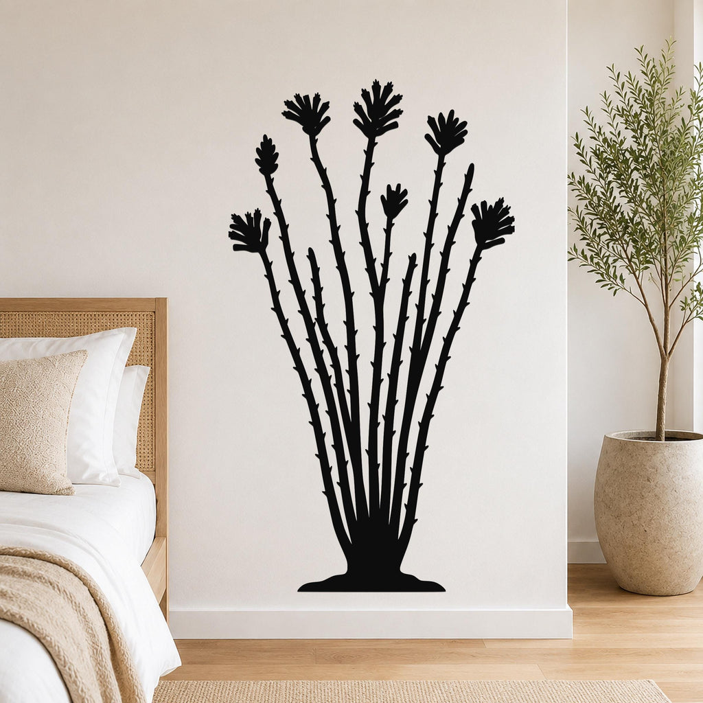 Black metal ocotillo wall sculpture with spiny stems and flower cutouts, mounted on a bedroom wall above a bed.