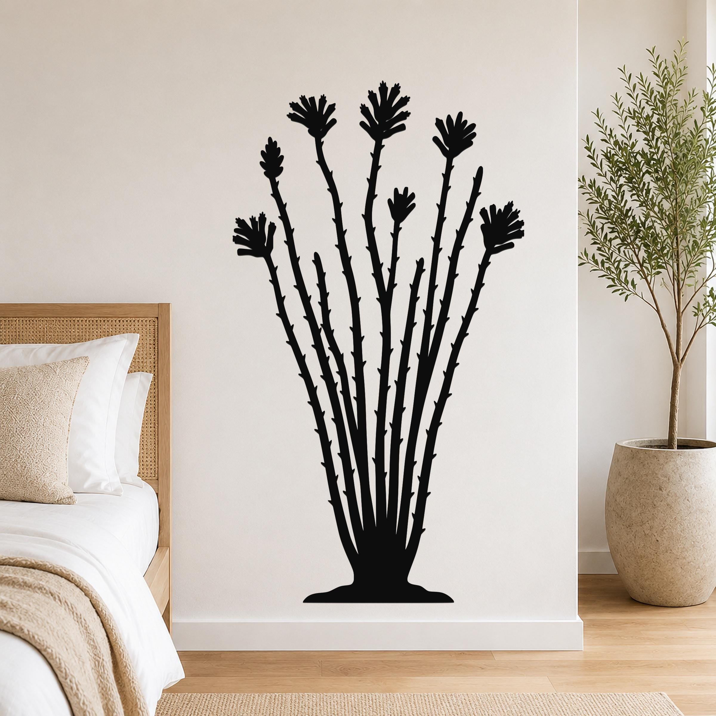 Black metal ocotillo wall sculpture with spiny stems and flower cutouts, mounted on a bedroom wall above a bed.