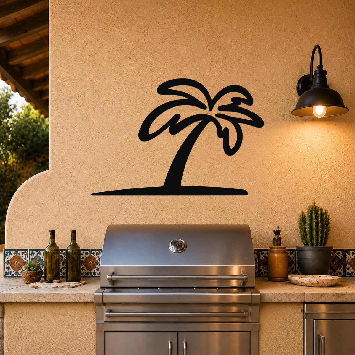 Black metal palm tree wall art silhouette mounted on a stucco wall above a stainless steel grill in an outdoor kitchen.