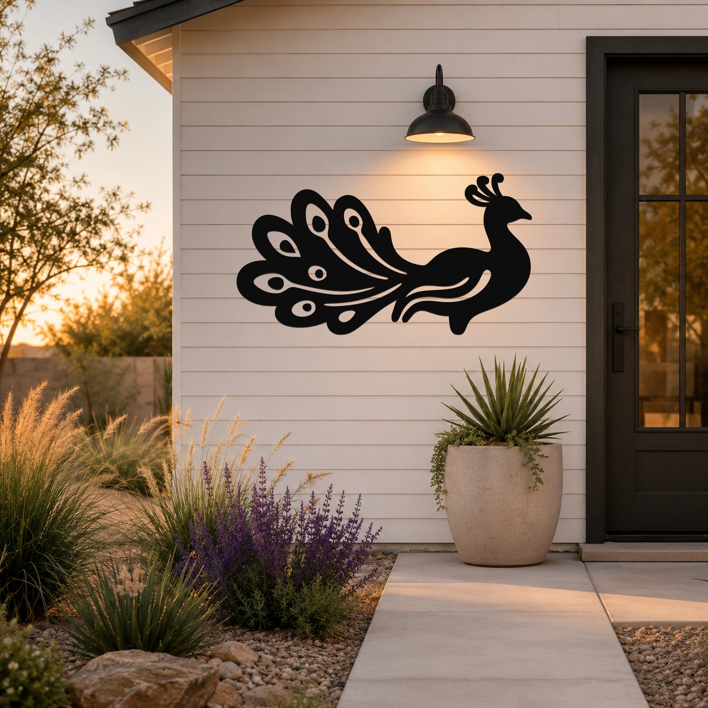 Black metal peacock wall art with detailed feather cutouts, mounted on a white siding wall beside a front door and potted plant.