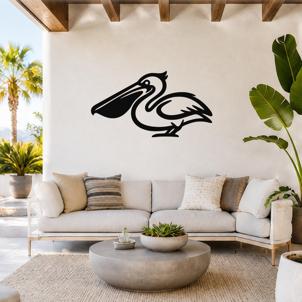 Black metal pelican wall art silhouette mounted above a white sofa in a bright, coastal-style living room.