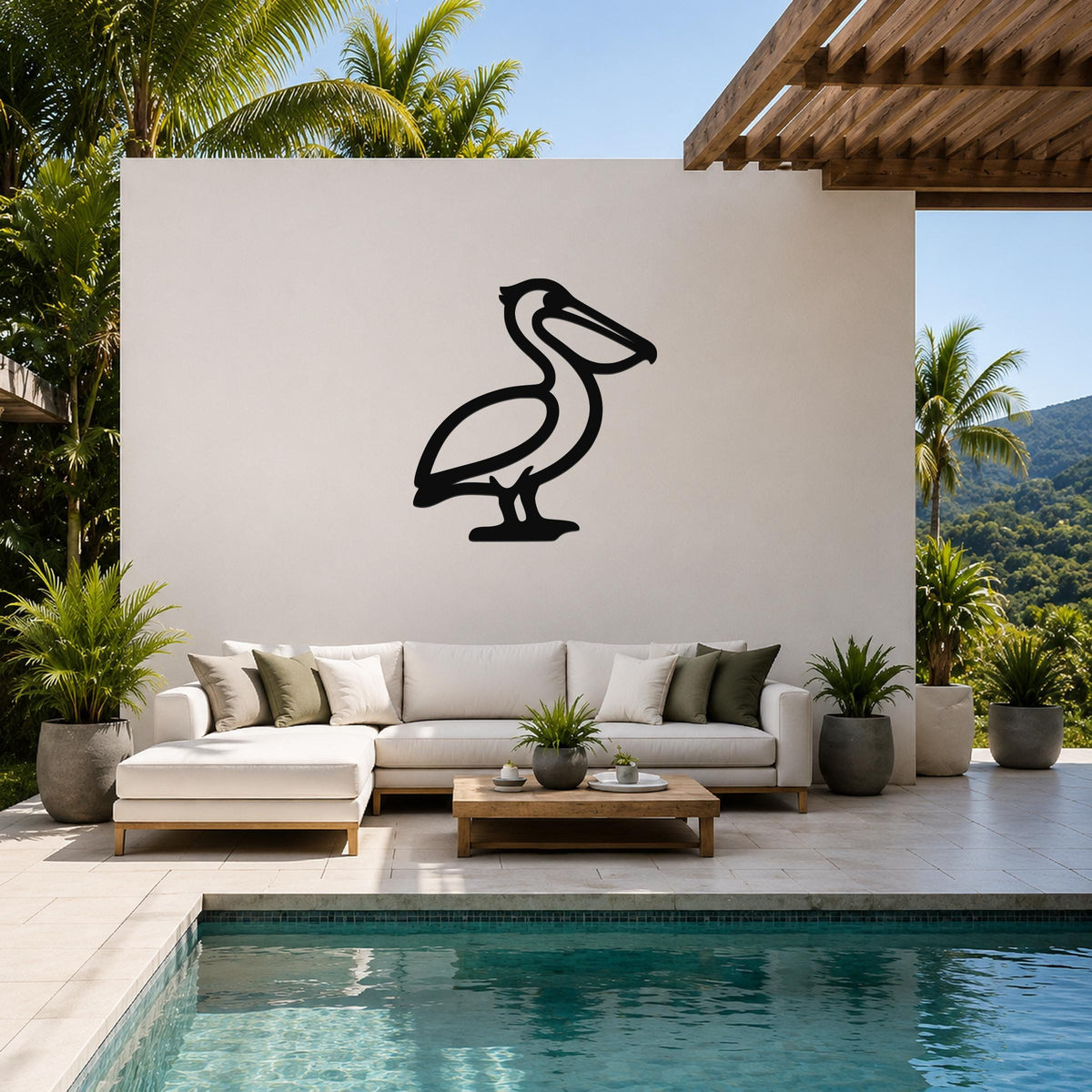 Black metal pelican wall art silhouette mounted on a white outdoor wall above a white sectional sofa in a tropical patio setting.