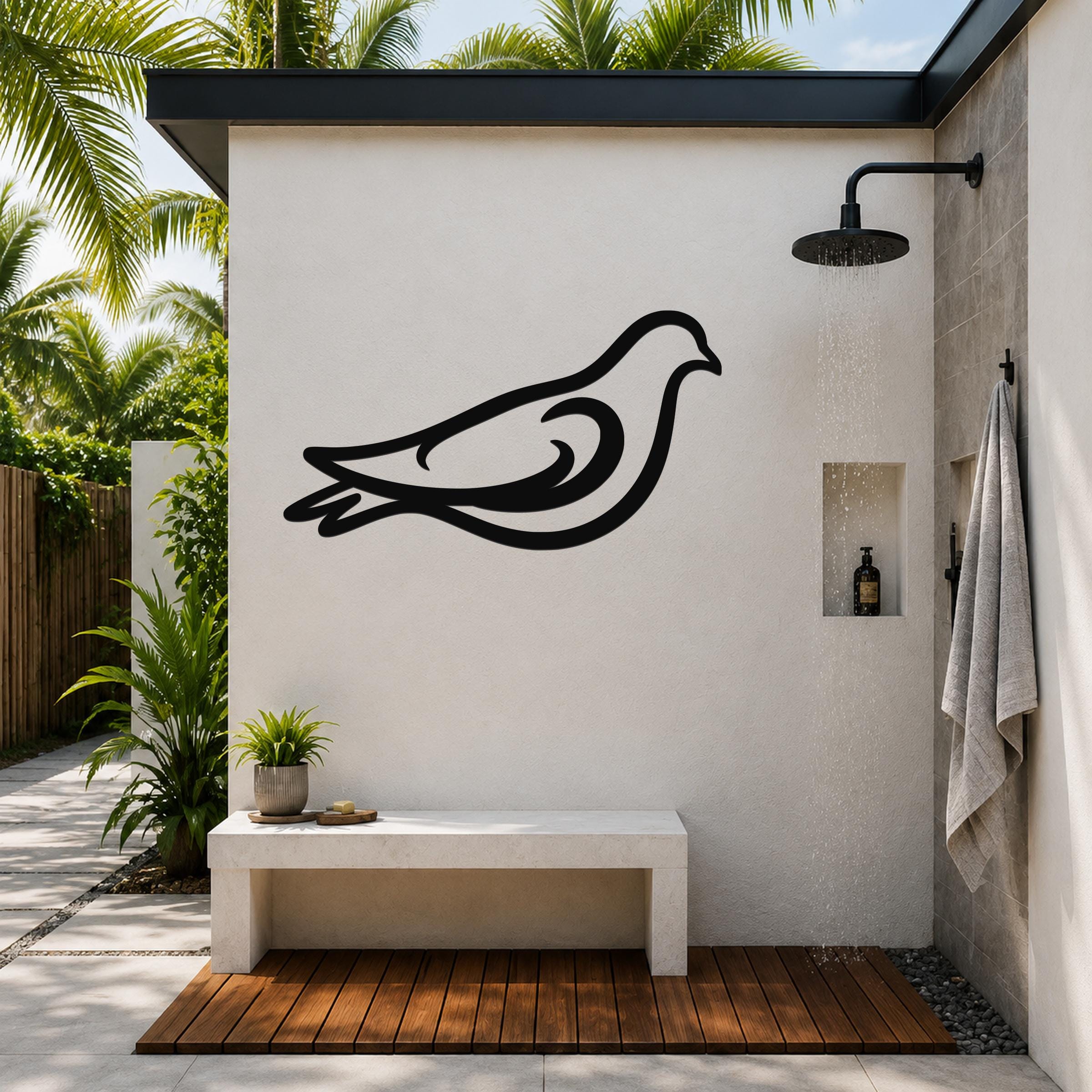 Black metal pigeon wall art silhouette mounted on a white outdoor shower wall, above a concrete bench in a tropical patio setting.