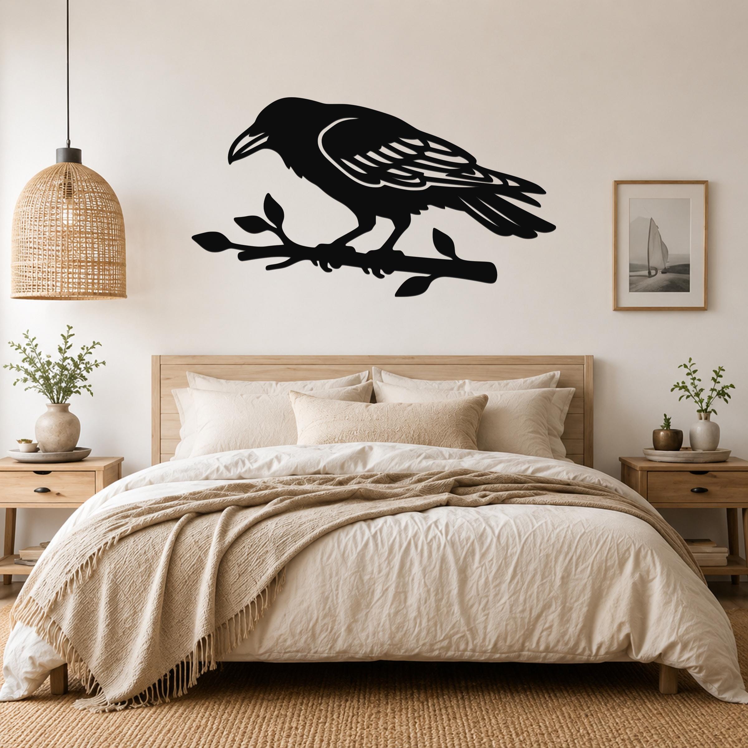 Black metal raven wall art cutout perched on a branch, mounted above a bed in a neutral bedroom.