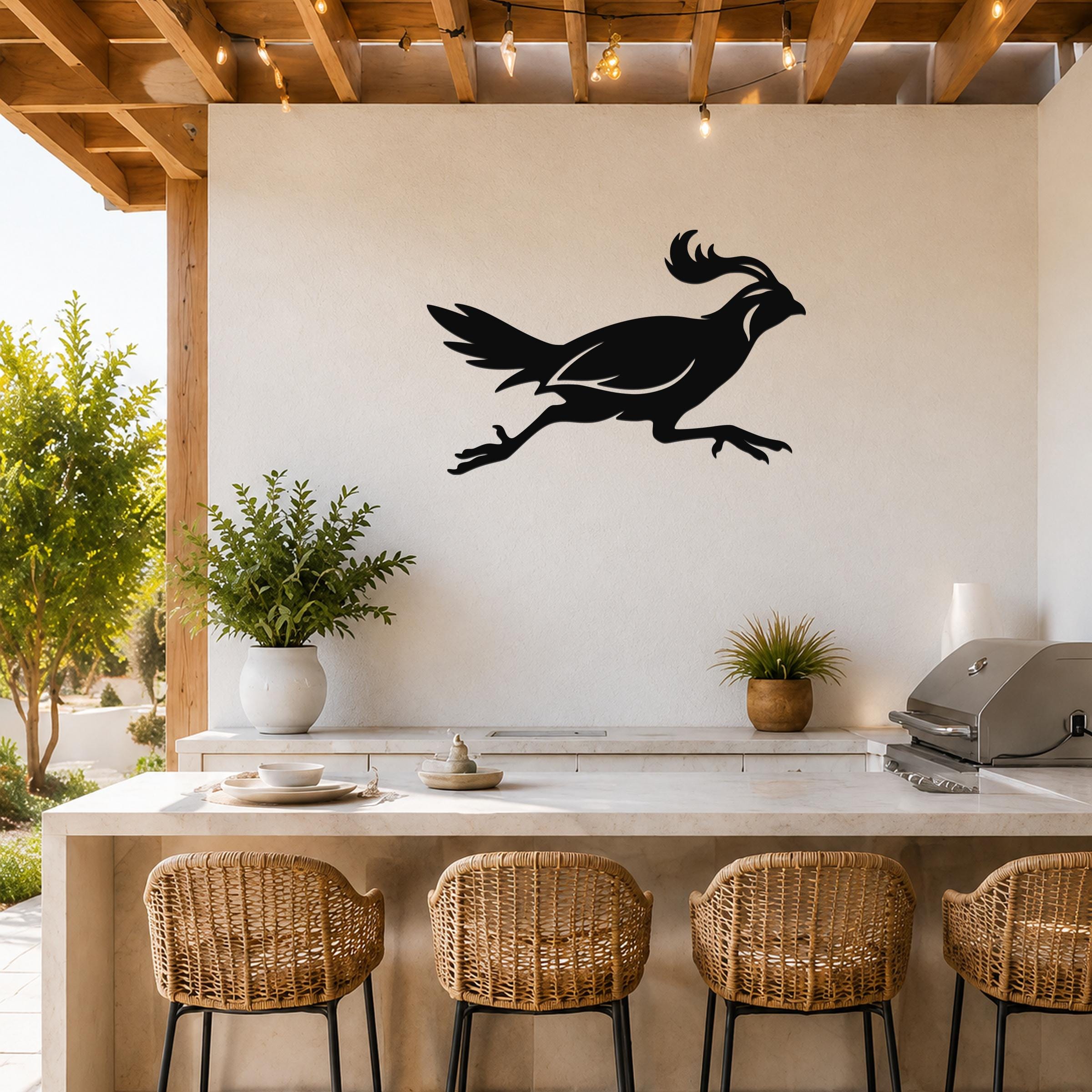 Black metal quail wall art in a running silhouette, mounted on a white outdoor kitchen wall above a counter with wicker bar stools.