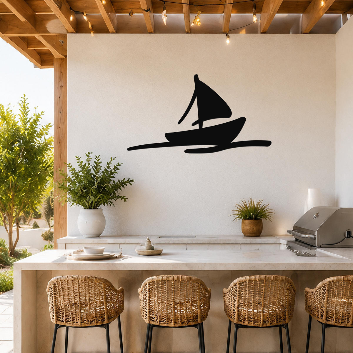 Black metal sailboat wall art silhouette mounted on a white outdoor kitchen wall above a counter with wicker bar stools.