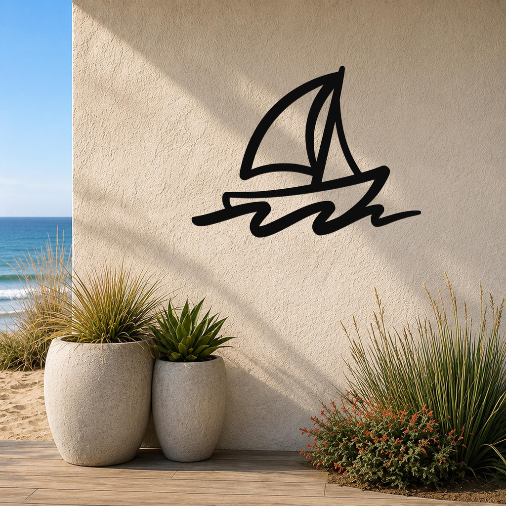 Black metal sailboat wall art with bold lines and wave cutouts, mounted on an outdoor wall beside potted plants and a beach view.