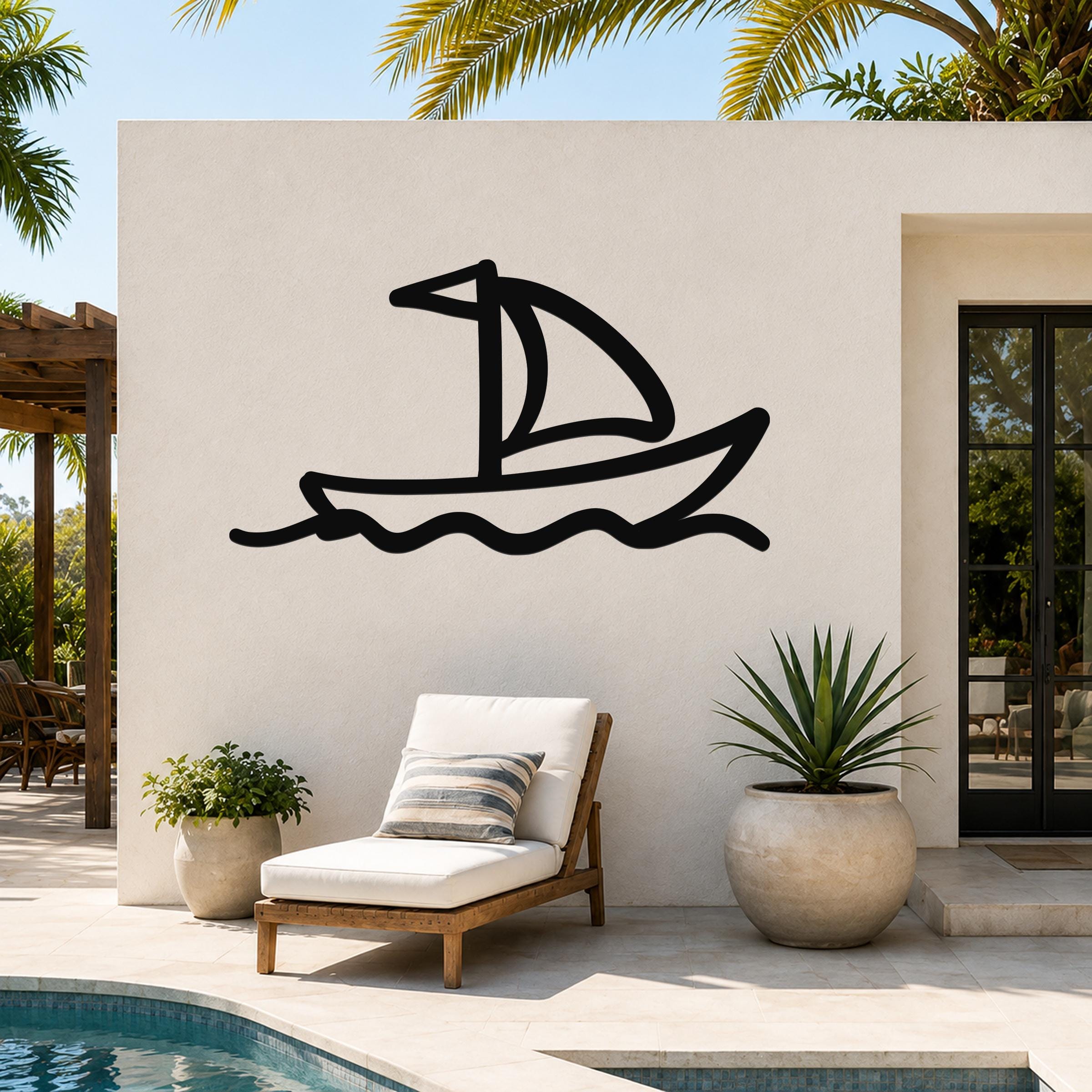 Black metal sailboat wall art with wavy water lines, mounted on an outdoor patio wall above a lounge chair.