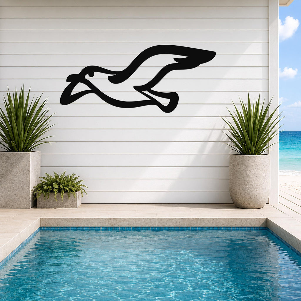 Black metal seagull wall art with motion-line cutouts, mounted on a white shiplap wall above a pool in a coastal outdoor space.