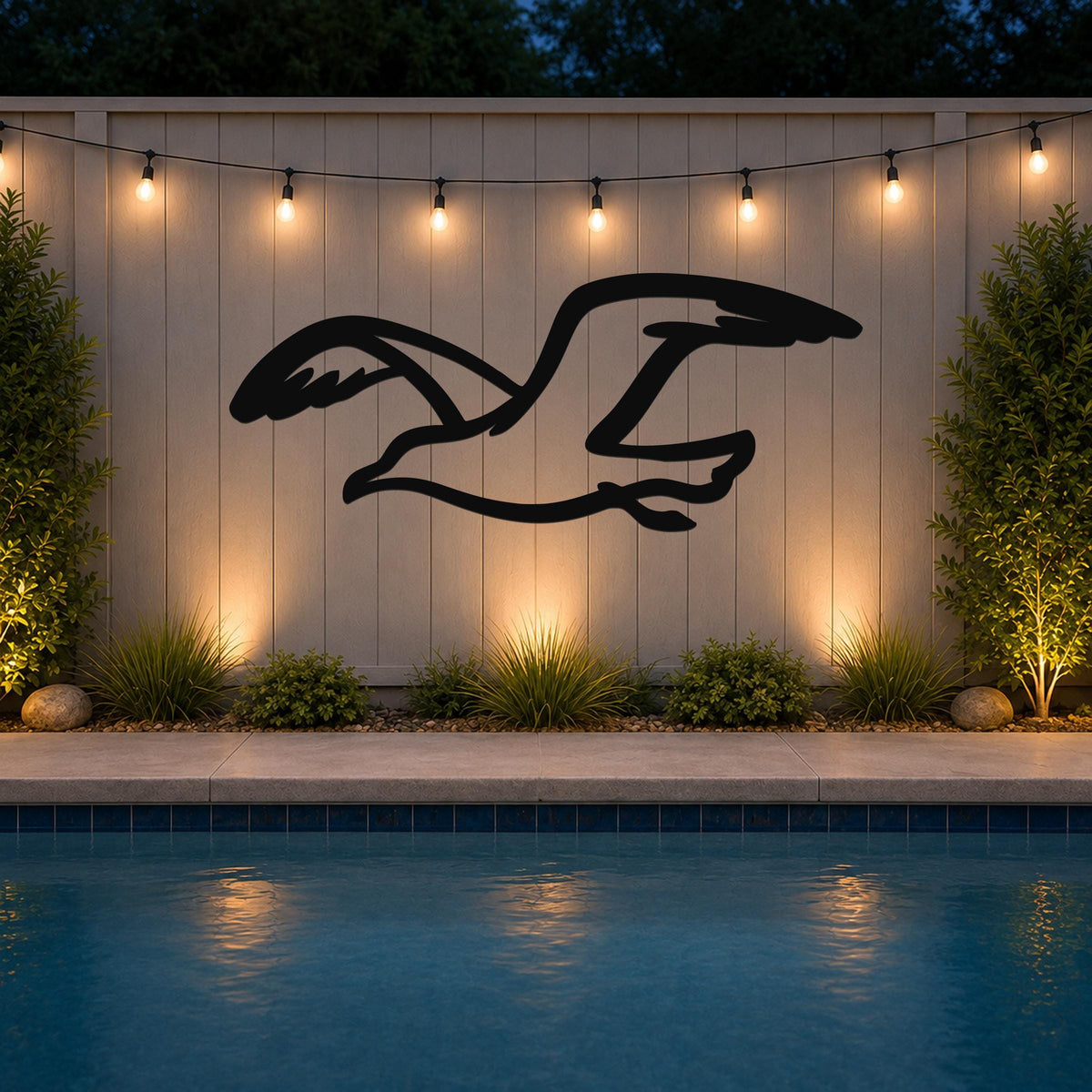 Black metal seagull wall art with motion-line cutouts, mounted on a light-colored outdoor wall above a pool at dusk.