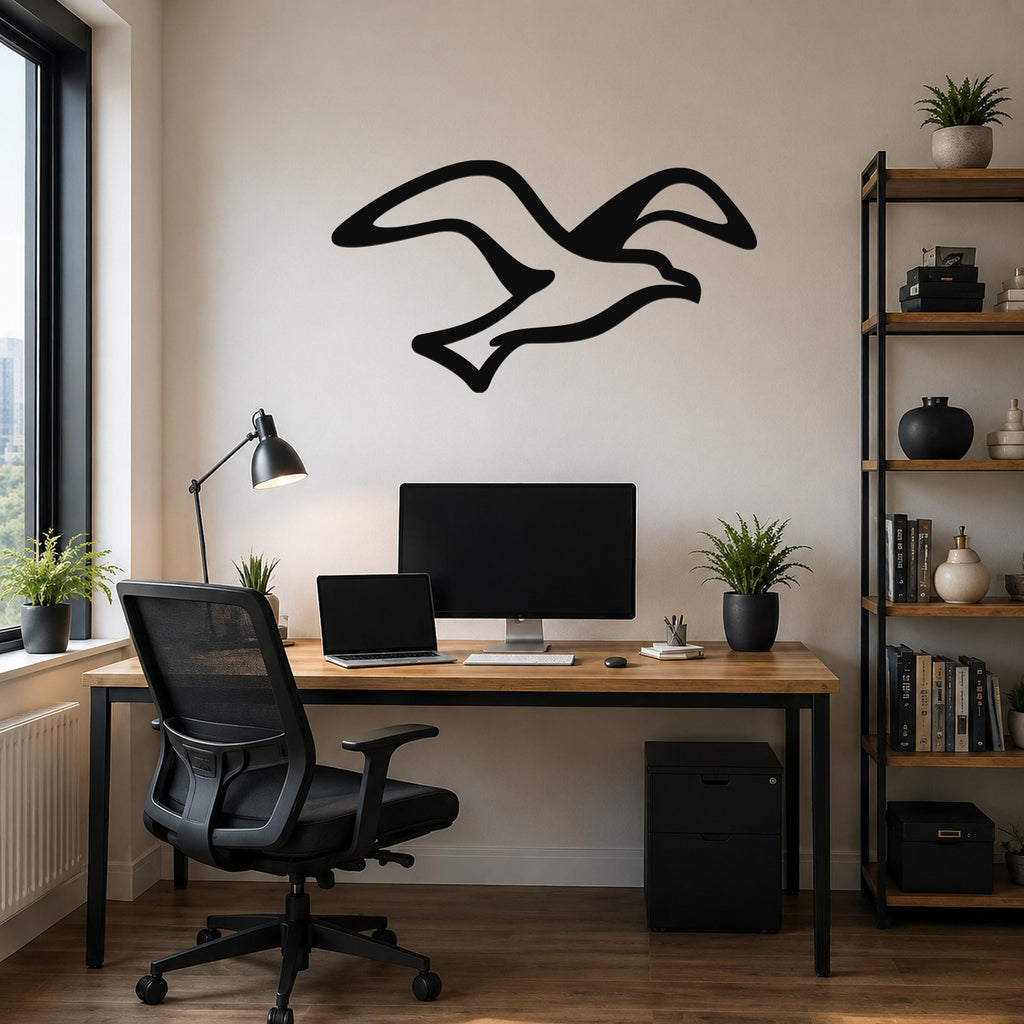 Black metal seagull wall art with flowing wing cutouts, mounted above a wooden desk in a modern home office.