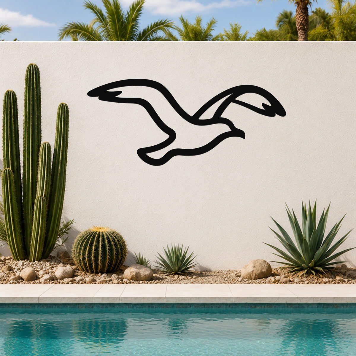Black metal seagull wall art with a flowing silhouette, mounted on an outdoor wall above a pool with cacti and palm trees in the background.