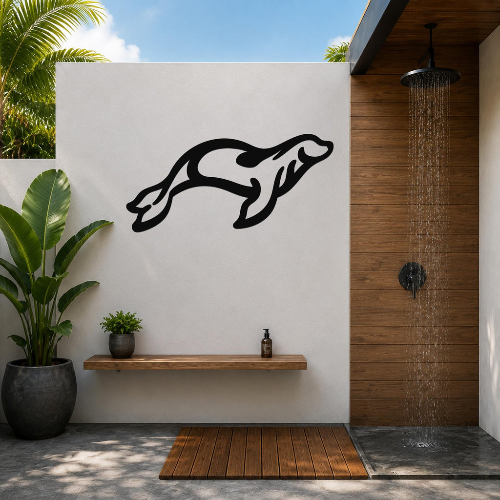 Black metal sea lion wall art in a leaping silhouette, mounted on a white outdoor wall above a wooden shelf in a tropical shower area.