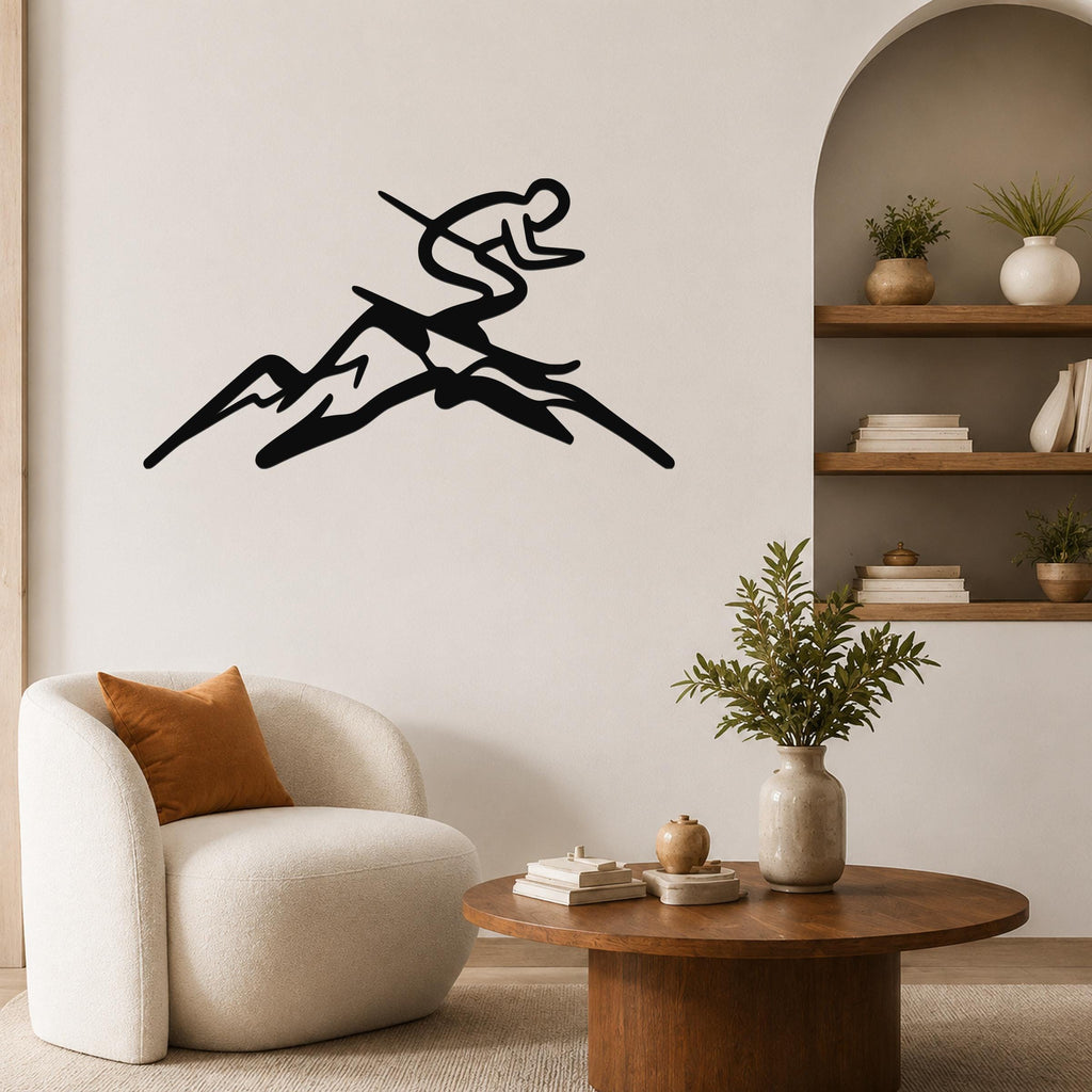 Black metal wall art featuring a skier silhouette in motion above mountain peaks, mounted on a living room wall above a white armchair.