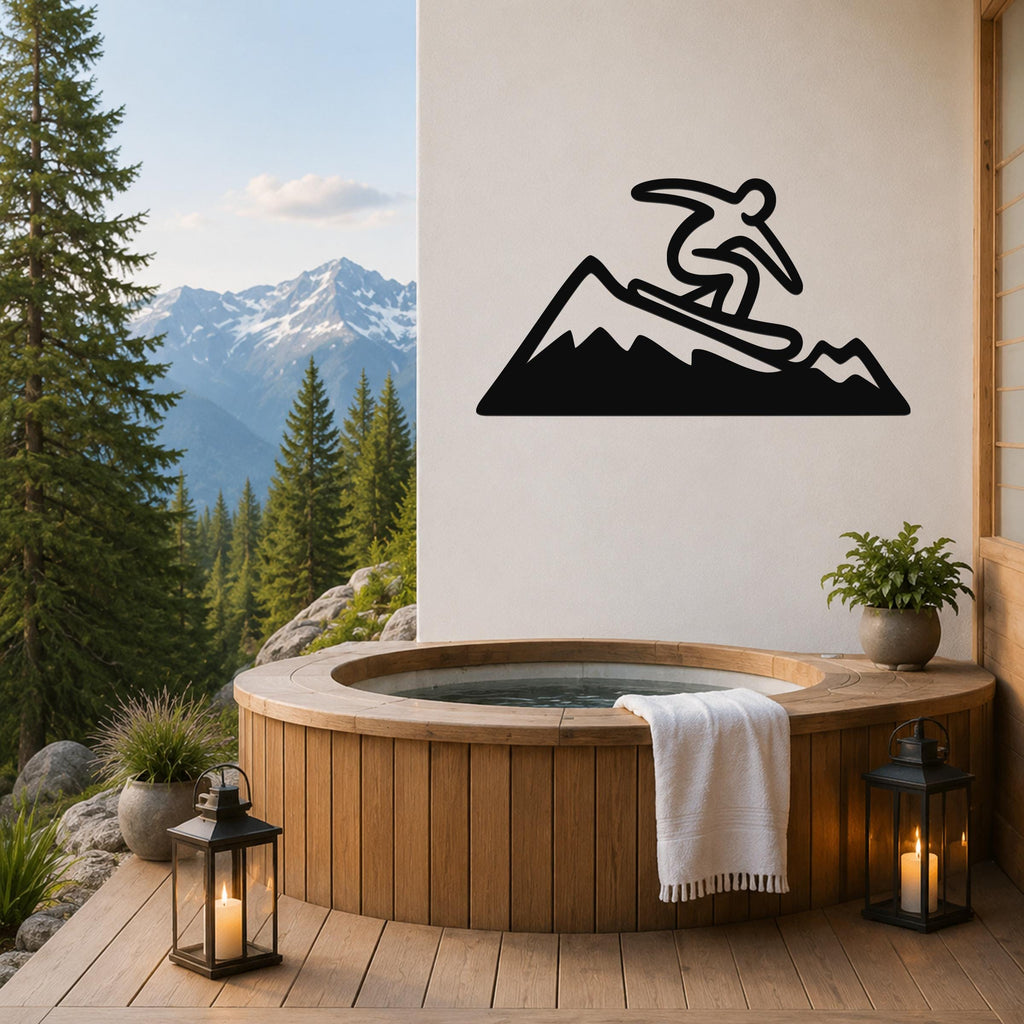 Black metal wall art silhouette of a snowboarder on a mountain, mounted on a white wall above a wooden hot tub on a deck with a mountain view.