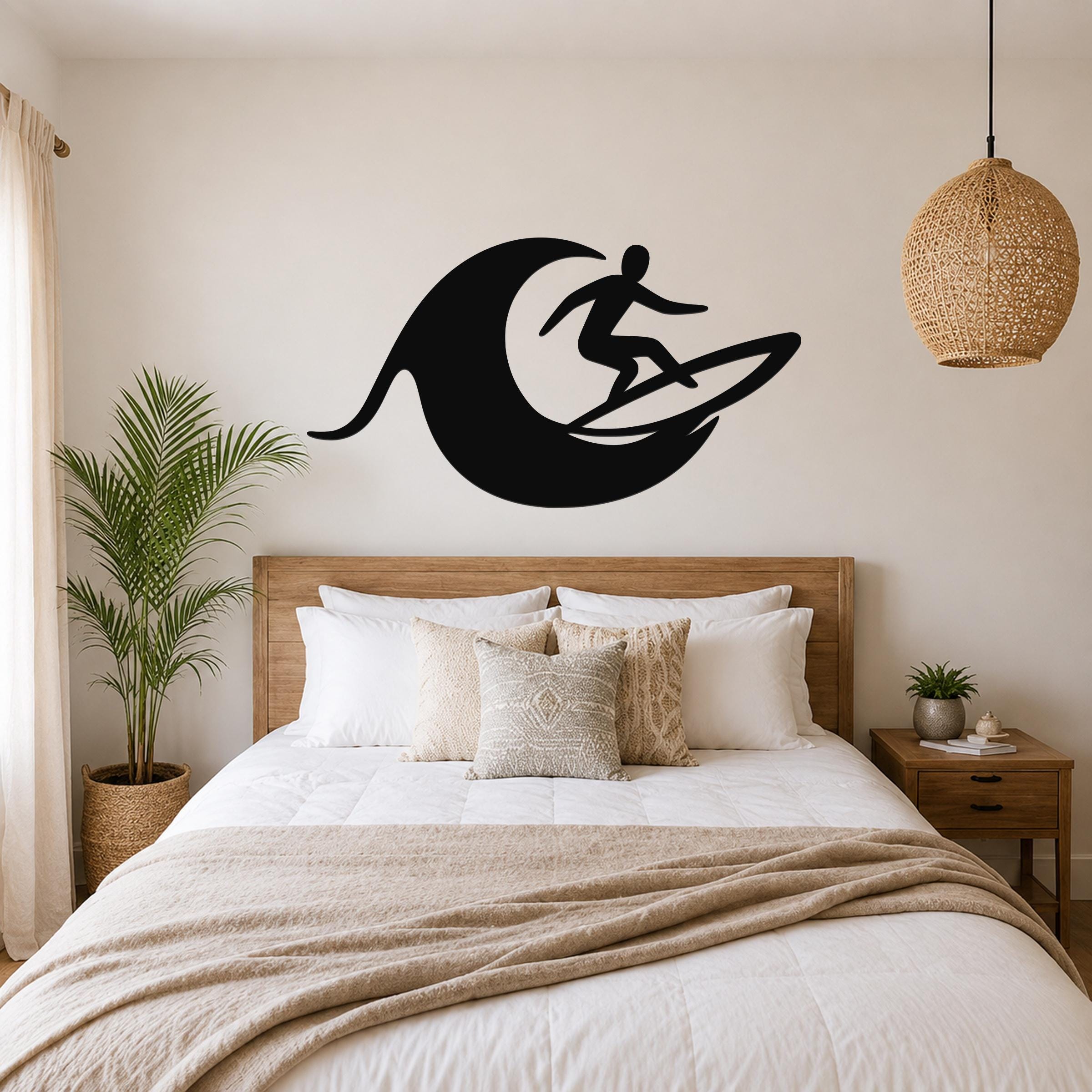 Black metal wall art featuring a surfer silhouette riding a wave, mounted above a wooden bed in a bedroom.