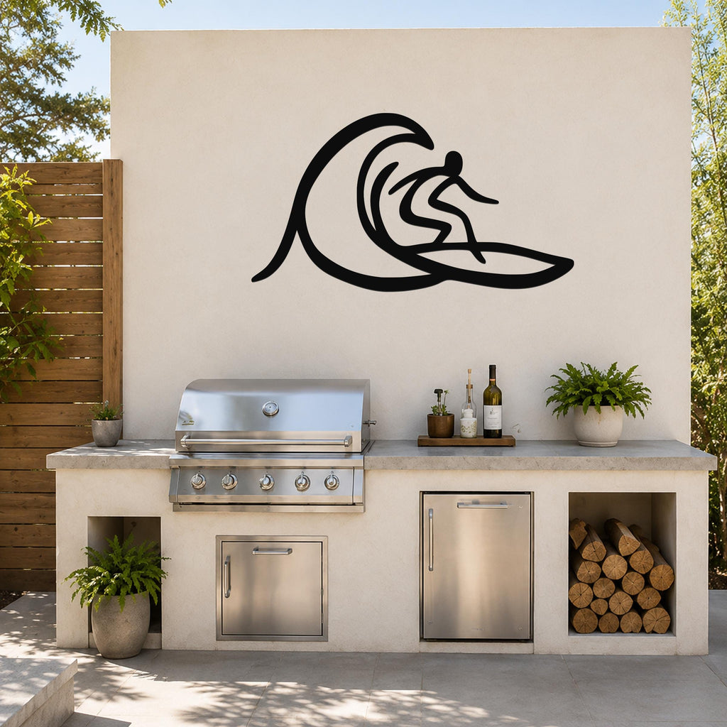 Black metal surfer wall art with wave silhouette, mounted on an outdoor kitchen wall above a stainless steel grill and counter.