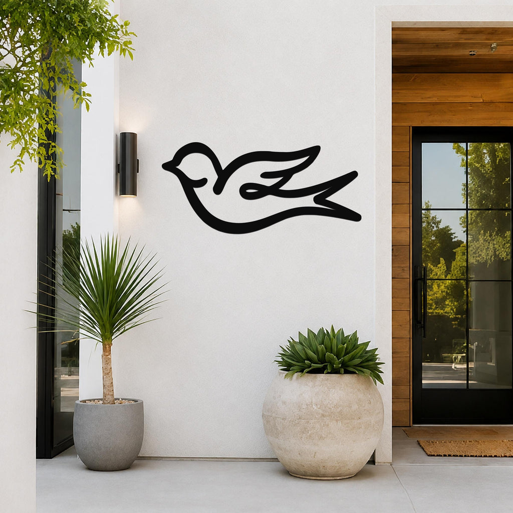 Black metal swallow bird wall art with a graceful silhouette, mounted on a white exterior wall beside a glass door and potted plants.