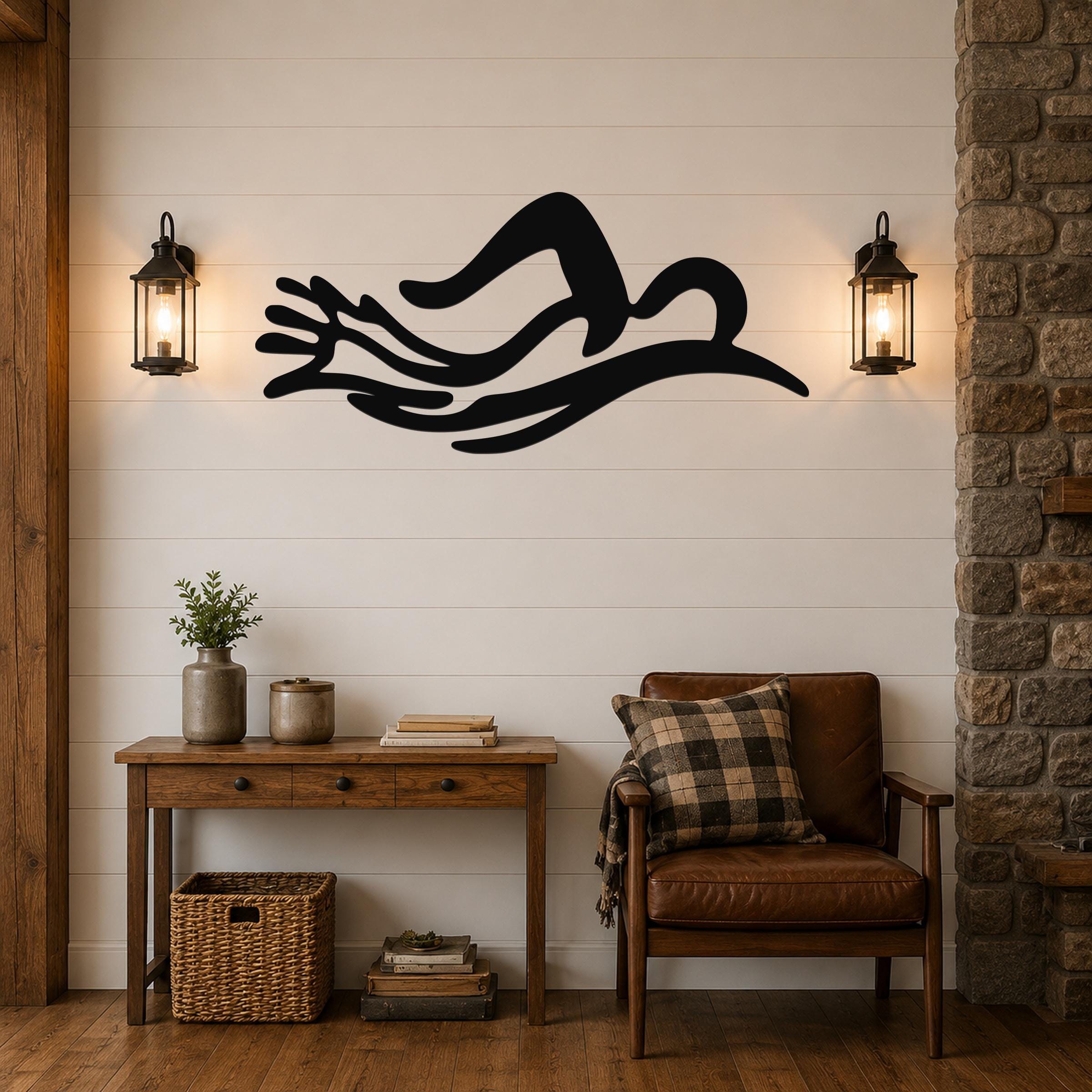Black metal wall art in the silhouette of a swimmer in motion, mounted above a wooden console table in a living room.