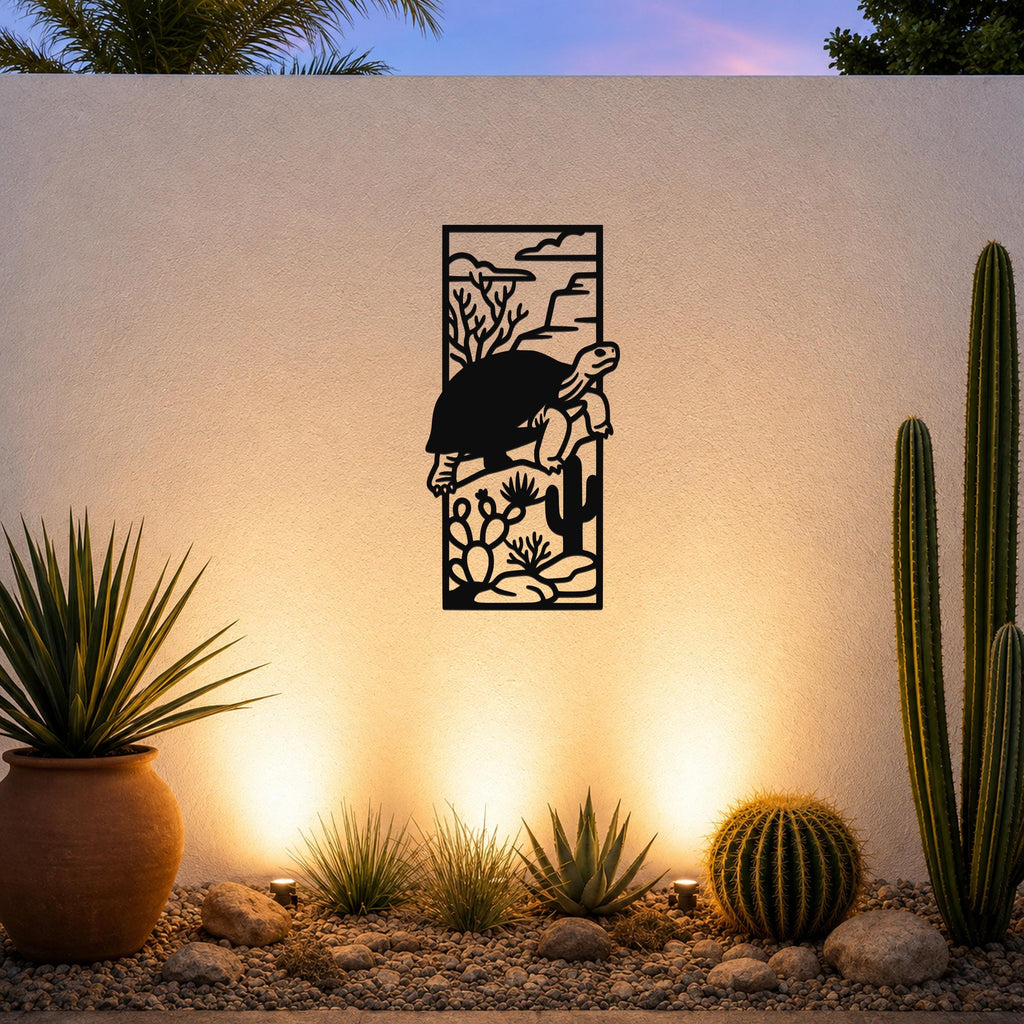 Black metal tortoise wall art with desert landscape cutouts, mounted on an outdoor wall above a gravel garden with cacti and warm uplighting.