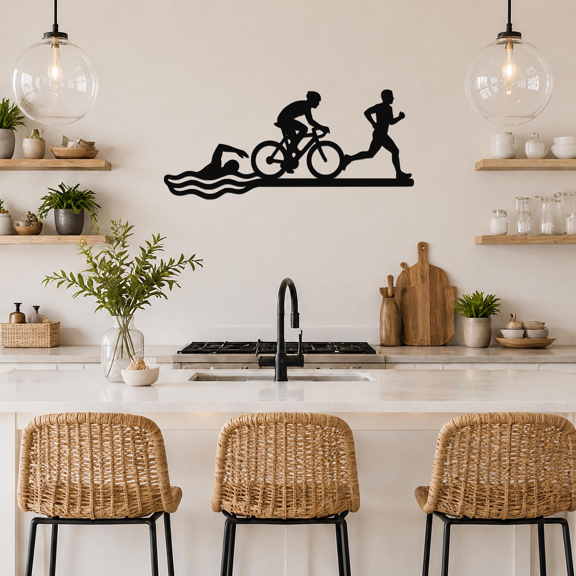 Black metal triathlon wall art with swim, bike, and run silhouettes, mounted above a kitchen counter.