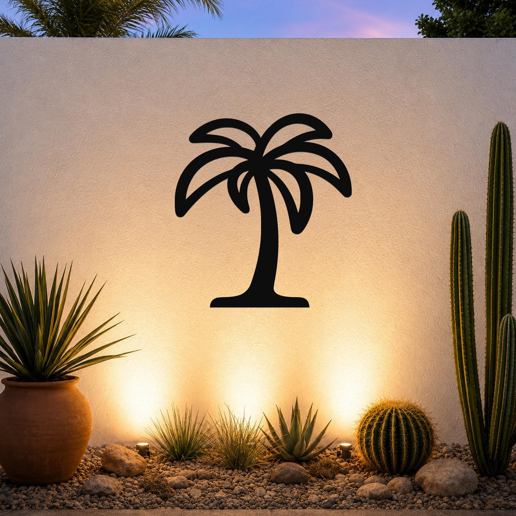 Black metal palm tree wall art with a silhouette design, mounted on an outdoor wall above a desert garden with cacti and warm uplighting.