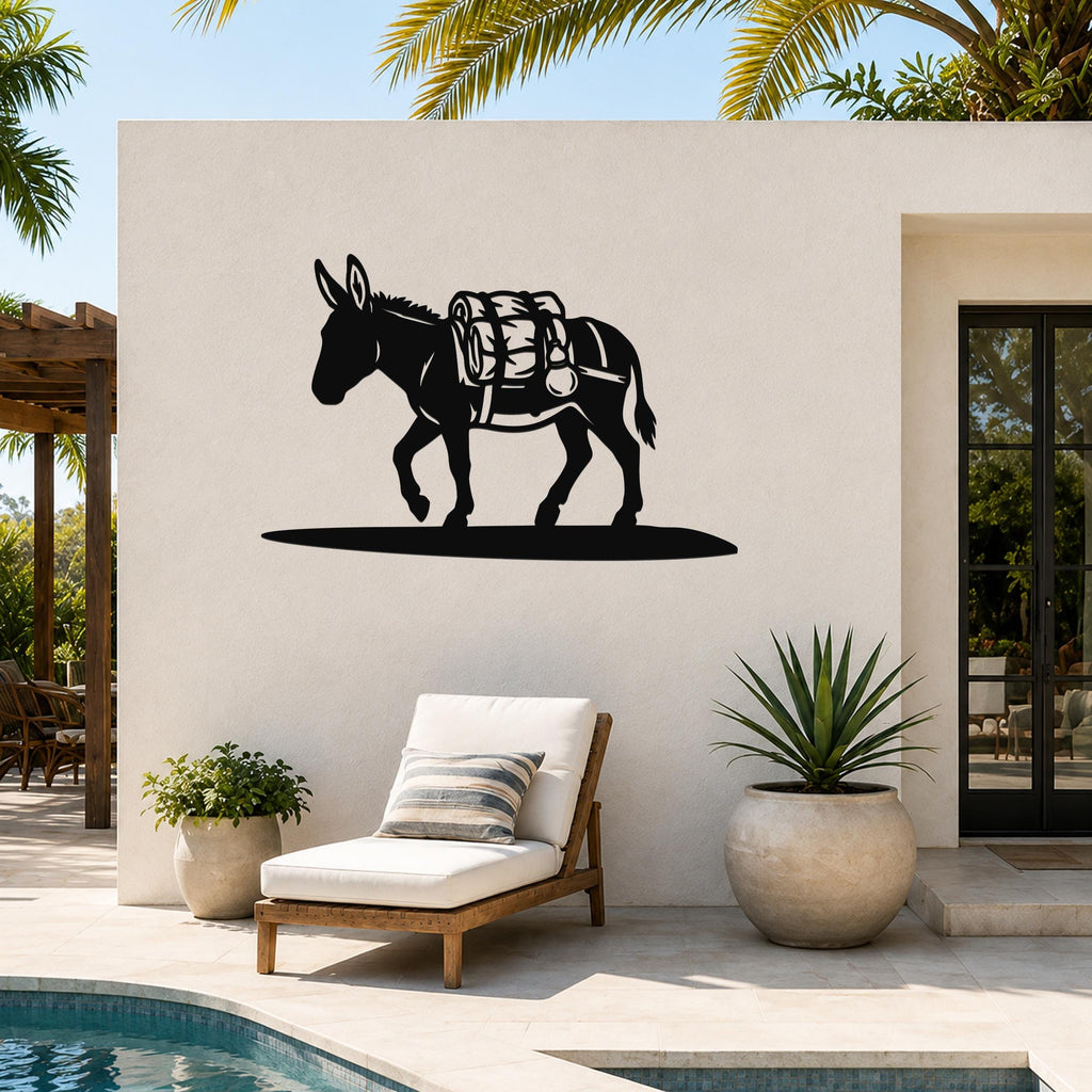 Black metal burro wall art with saddle and pack cutouts, mounted on an outdoor patio wall above a lounge chair.