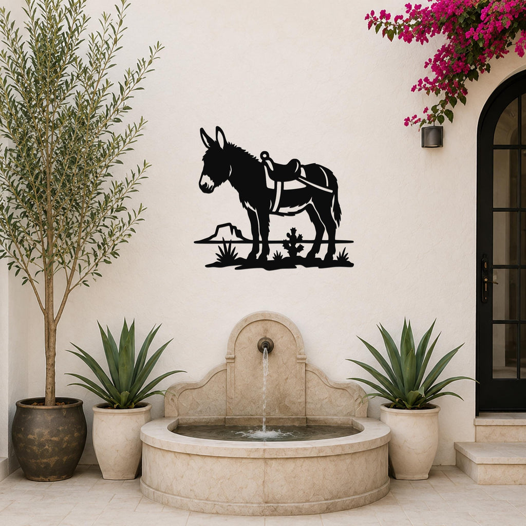 Black metal wall art silhouette of a burro with saddle, mounted on a stucco wall above a stone fountain in a patio setting.
