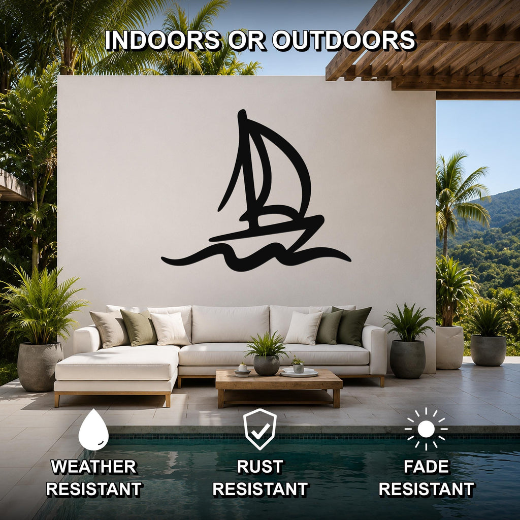 Black metal sailboat wall art with wave cutouts, mounted on a white outdoor wall above a sofa in a patio living area.