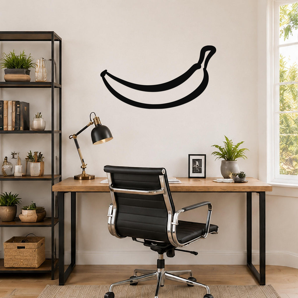 Black metal banana wall art silhouette mounted above a wooden desk in a home office.