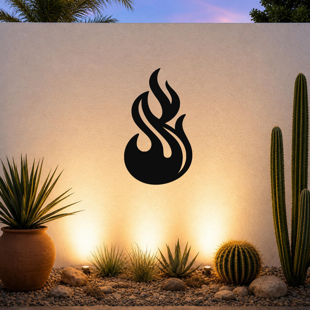 Black metal flame wall art with fluid, cutout design, mounted on an outdoor wall above a desert garden with cacti and warm uplighting.