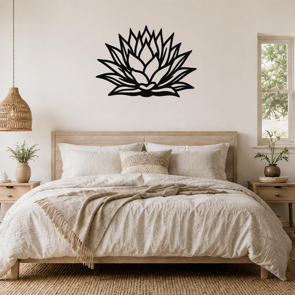 Black metal agave wall sculpture with layered leaf cutouts, mounted above a bed in a neutral bedroom.