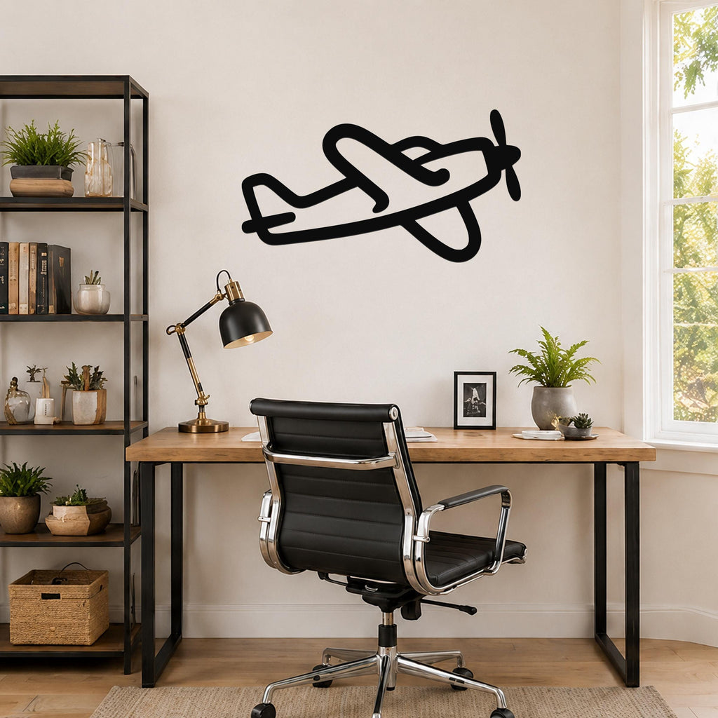 Black metal airplane wall art with a silhouette design, mounted on a wall above a wooden desk in a home office.