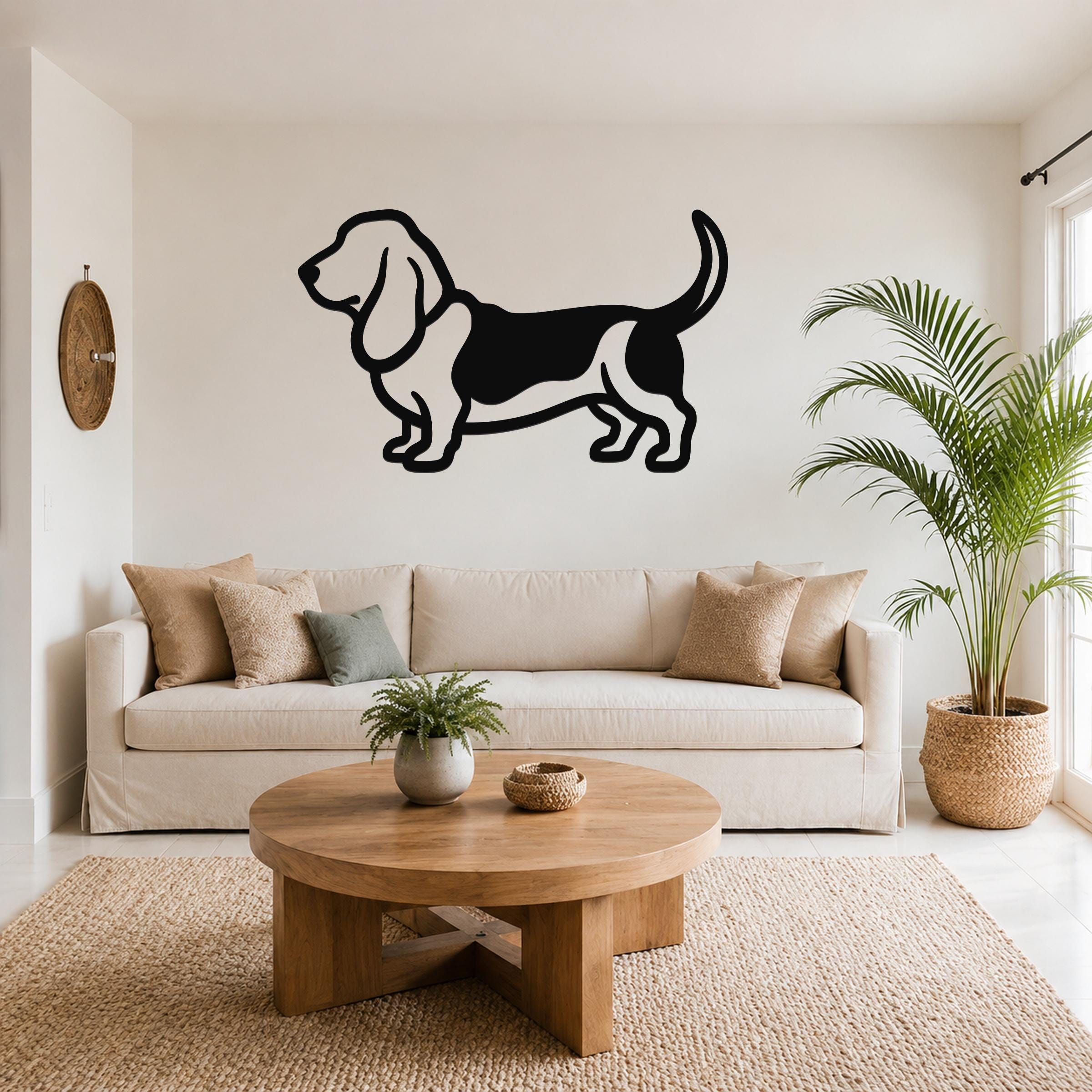 Black metal Basset Hound wall art silhouette mounted above a beige sofa in a living room.