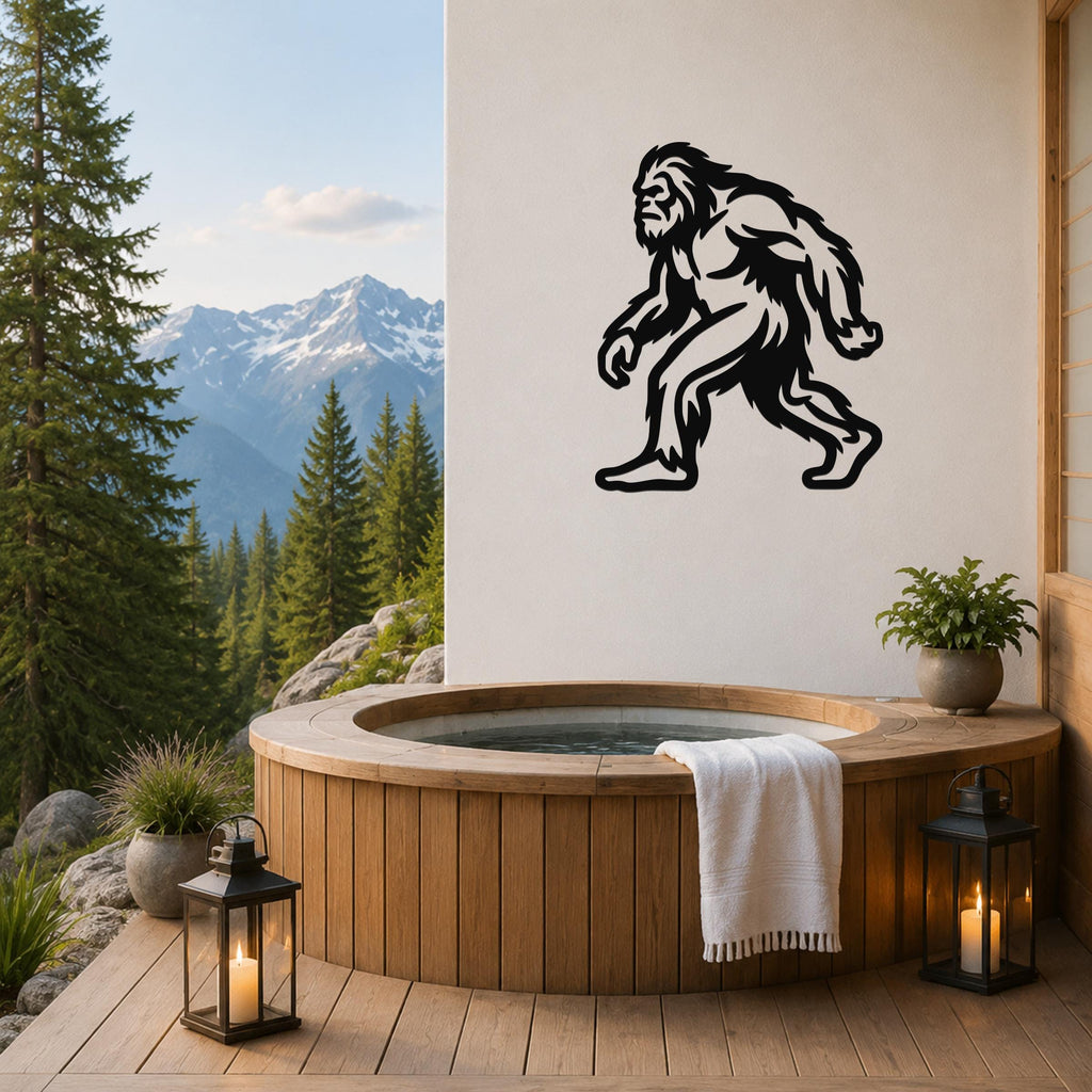 Black metal Bigfoot silhouette wall art mounted on a white wall above a wooden hot tub on a mountain-view deck.