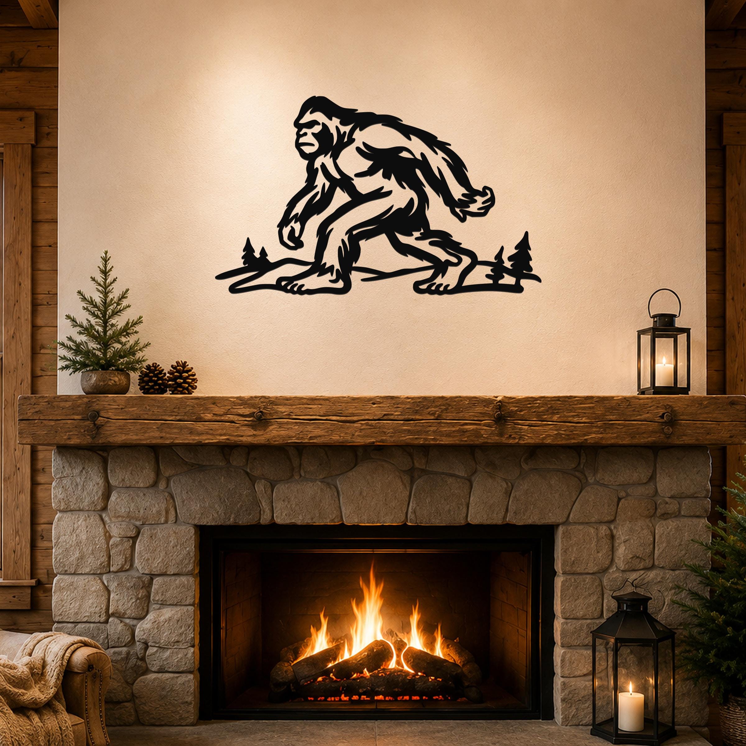 Black metal Bigfoot wall art silhouette with tree cutouts, mounted above a stone fireplace in a rustic living room.