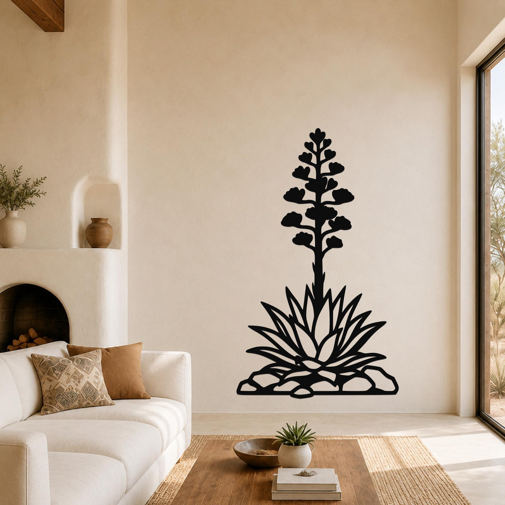 Black metal agave wall art with a blooming flower and spiky leaves cutout, mounted on a living room wall above a sofa.